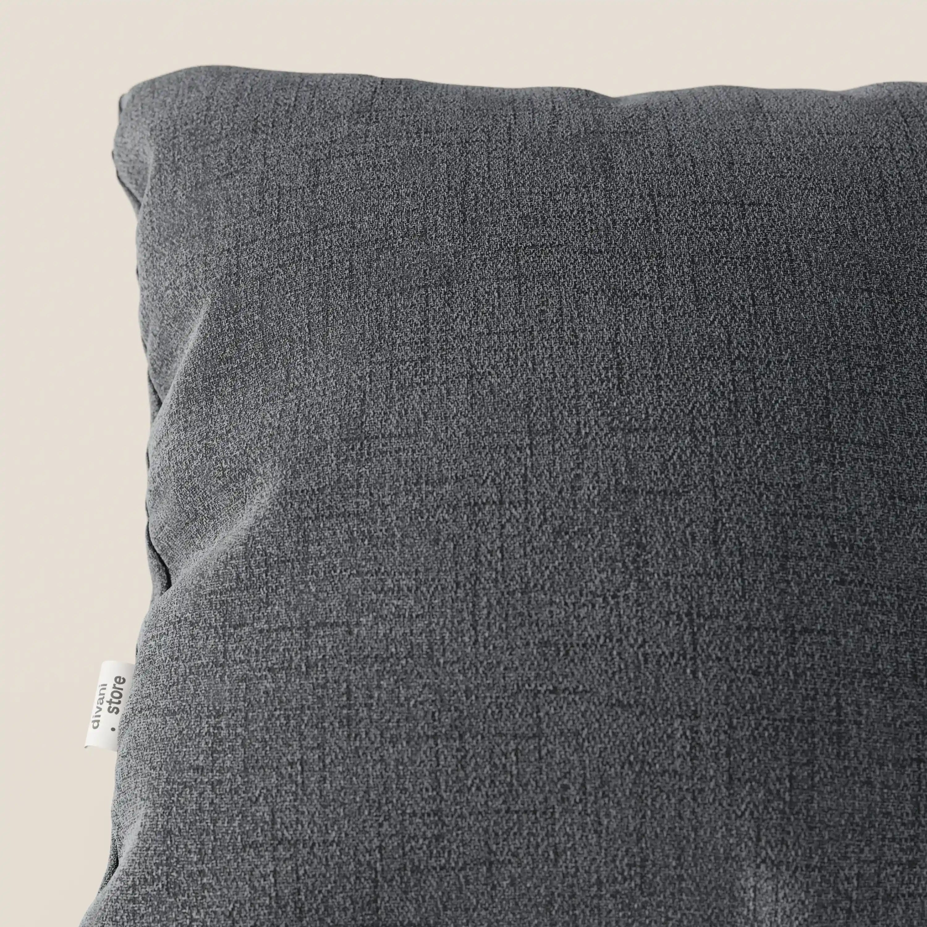 Primo piano del cuscino Felis di Divani.Store in T03 grigio, realizzato in morbido tessuto impermeabile dalla trama sottile. Sul bordo sinistro è applicata una piccola etichetta bianca con testo nero. Lo sfondo è un semplice beige chiaro.