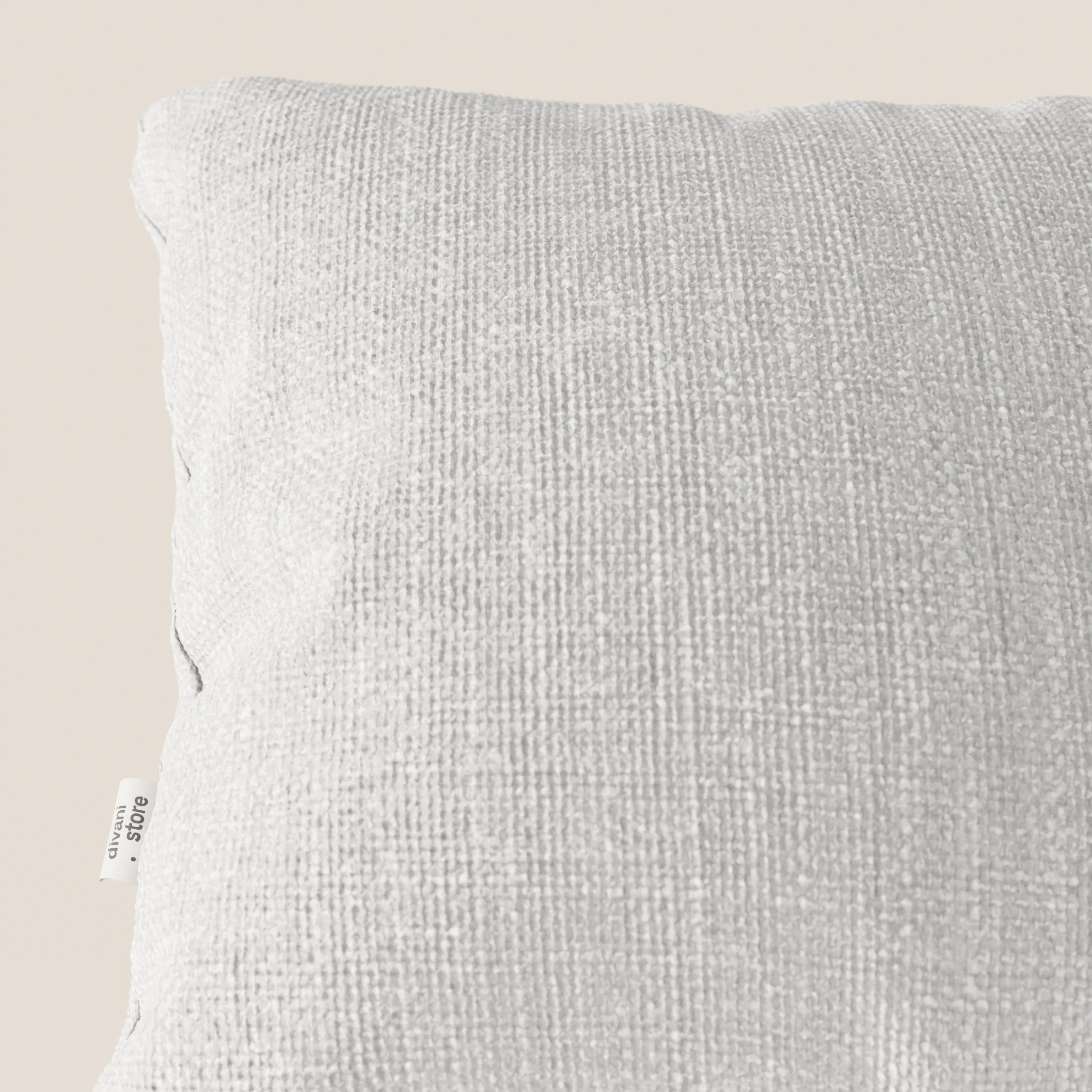 Primo piano del cuscino Lyon 45x45 cm in morbido tessuto intrecciato impermeabile T06 grigio chiaro di Divani.Store, su sfondo beige con etichetta bianca visibile che riporta le informazioni sul materiale. Il cuscino appare morbido e ben rifinito.