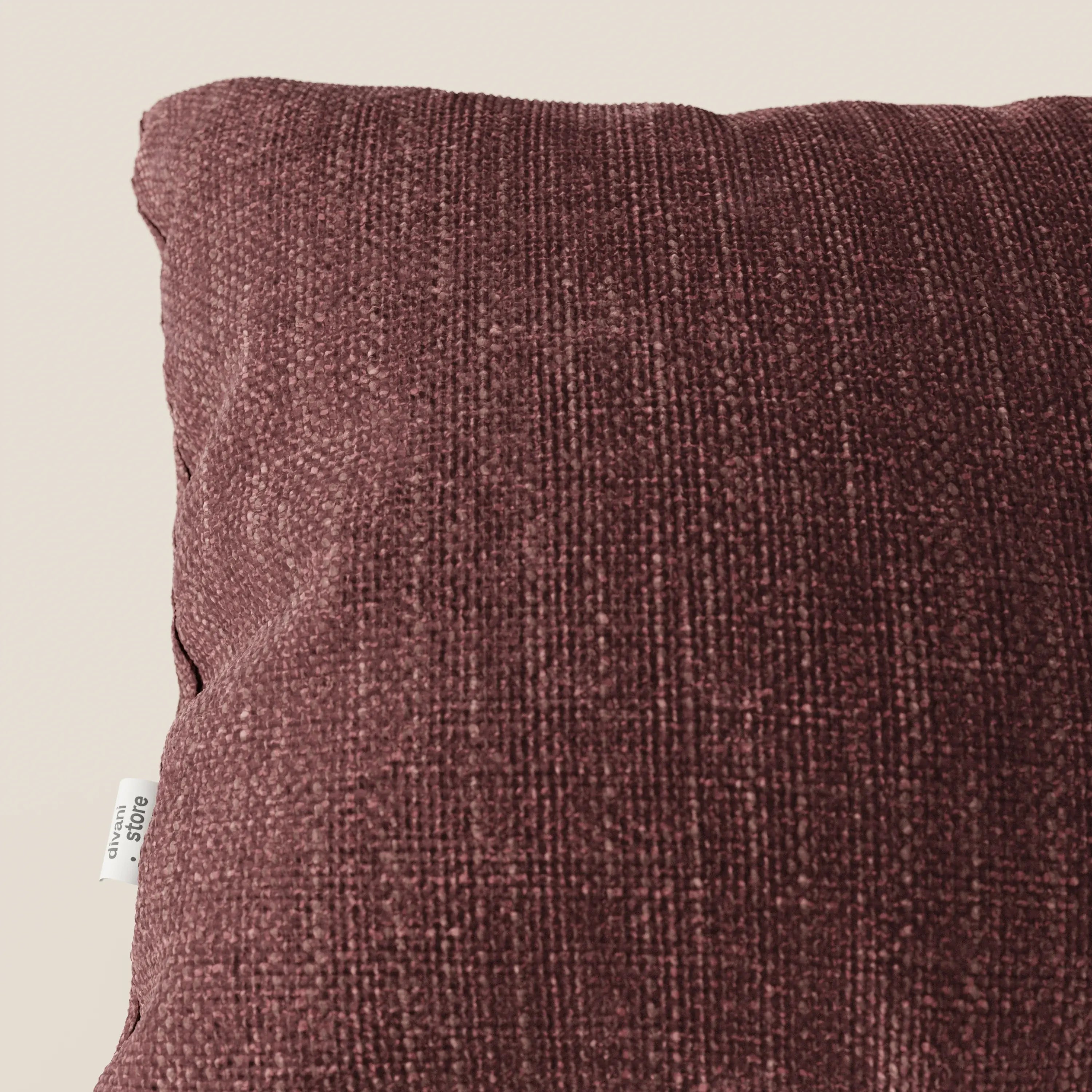 Primo piano del cuscino Lyon 45x45 cm di Divani.Store, in morbido tessuto intrecciato impermeabile T06 rosso. È visibile solo la parte superiore destra, che mette in evidenza il tessuto intrecciato e l'elegante piccola etichetta laterale bianca.