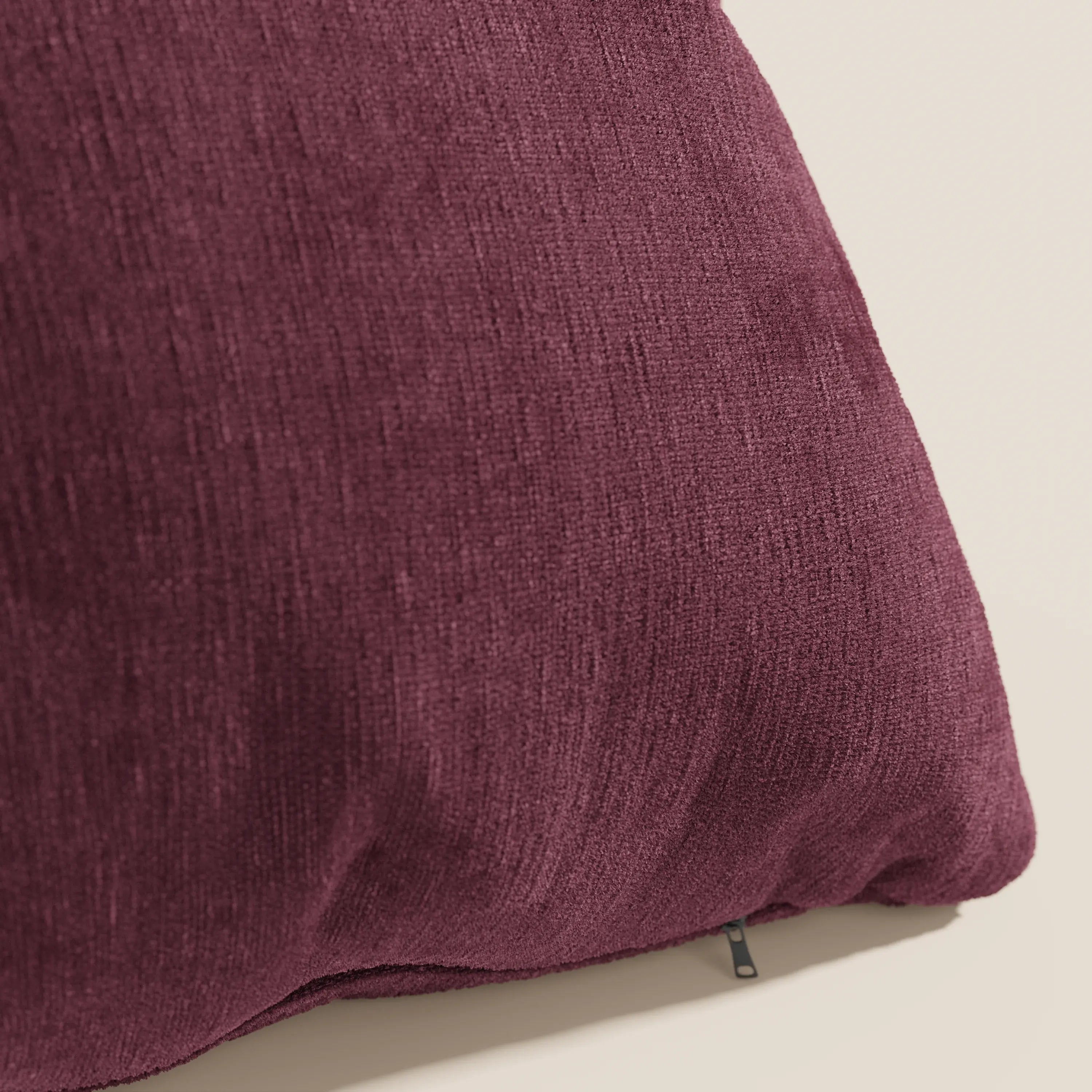Primo piano del cuscino Bolero di Divani.Store in colore marrone, con tessuto T31 morbido, antimacchia, impermeabile e non restringente. Una piccola cerniera nera è parzialmente visibile sul bordo inferiore destro su uno sfondo neutro.