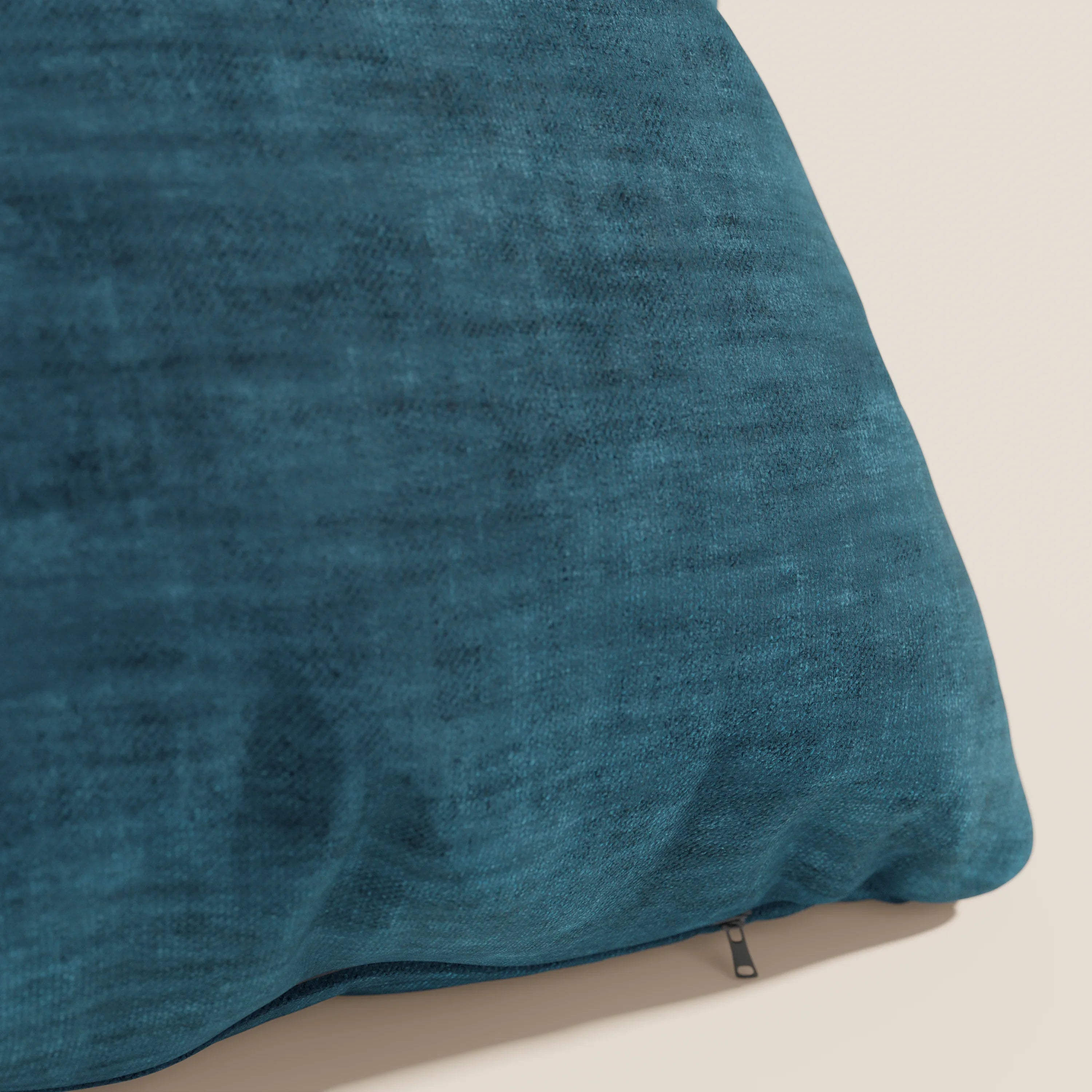 Un primo piano del cuscino Sofia di Divani.Store, presentato in un grande blu acqua. Realizzato in morbido velluto velato (smacchiabile e impermeabile Easy Clean T35) con cerniera a vista sul fondo, su uno sfondo beige chiaro.