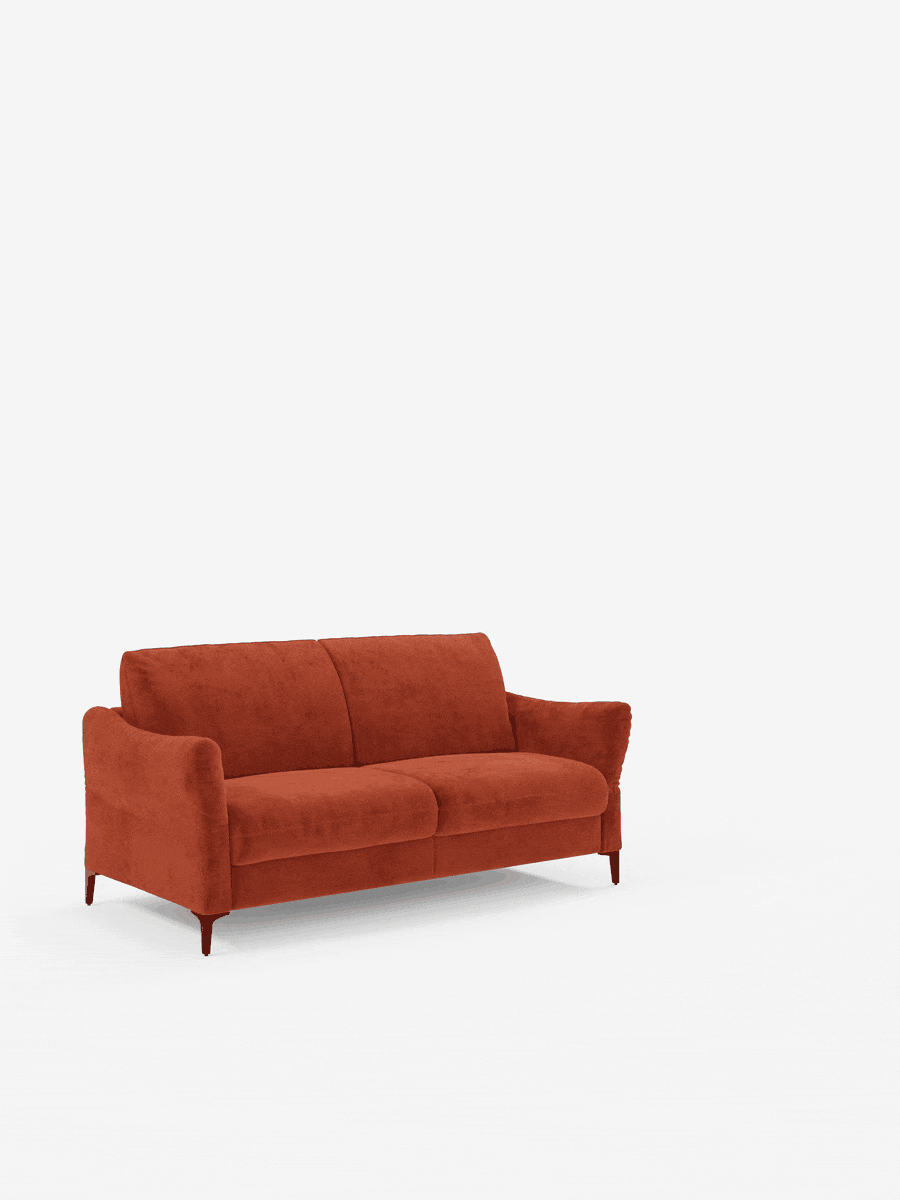 Un divano contemporaneo, il divano letto Dalia di Divani.Store, rivestito in tessuto T30 vellutino smacchiabile color arancio bruciato, poggia su sottili gambe in legno con braccioli leggermente ricurvi su uno sfondo bianco. Questo divano in stile scandinavo presenta un design minimalista, linee pulite, due cuscini di seduta e uno schienale alto. L’immagine ben illuminata mette in risalto la trama del divano e il suo fascino moderno.
