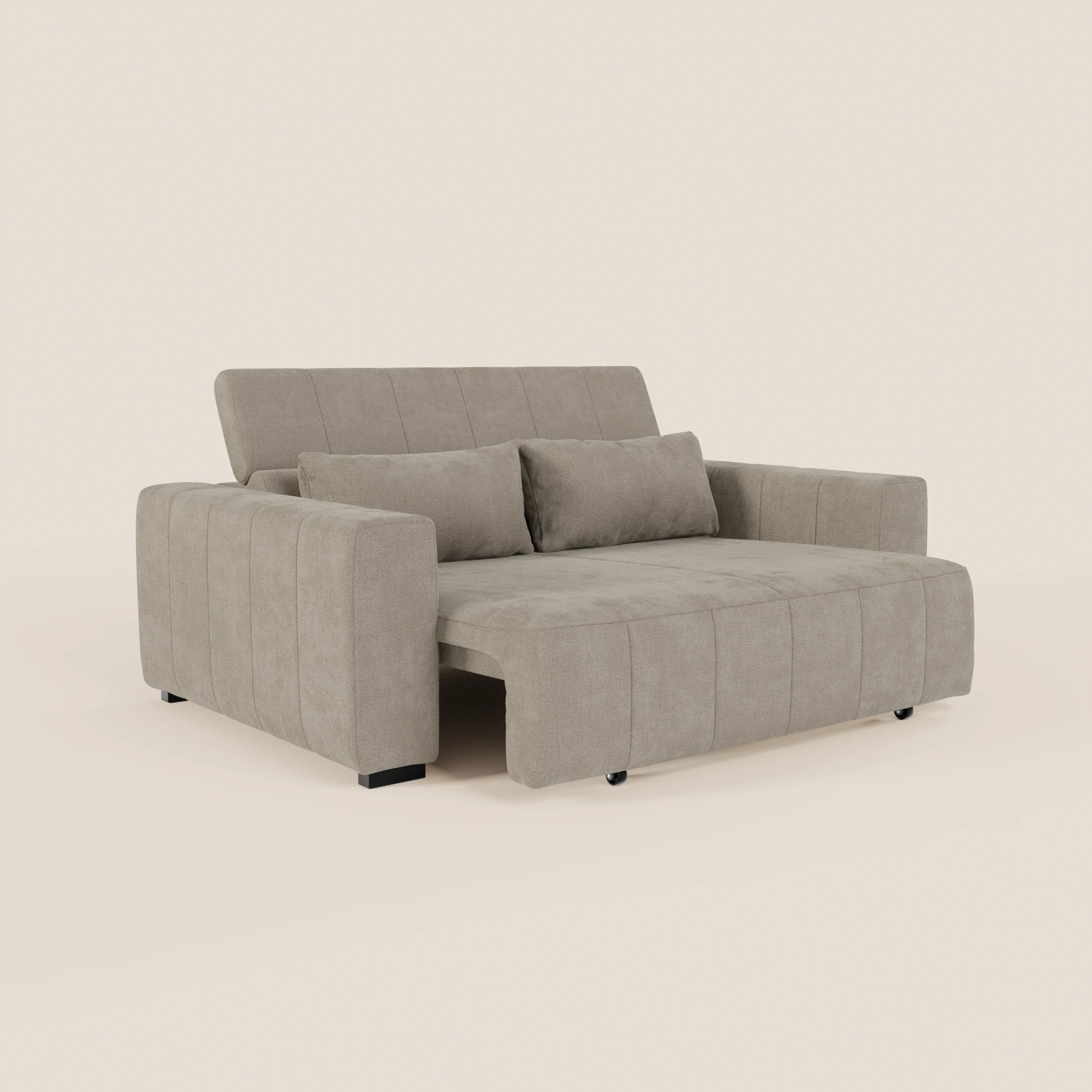 Il divano Doric 3 posti di Divani.Store è caratterizzato da un tessuto T23 antimacchia di colore beige chiaro, ampi braccioli, due cuscini in tinta, poggiatesta reclinabili e sedute allungabili elettricamente a formare una chaise lounge. Si regge su corte gambe nere su uno sfondo chiaro.