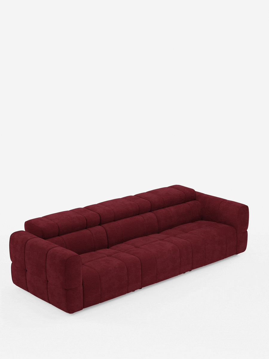 Un moderno divano modulare Giotto a 4 posti con poggiatesta reclinabili e funzione relax elettrica opzionale, rivestito in tessuto smacchiabile T23 color bordeaux intenso, caratterizzato da un design a segmenti trapuntato, braccioli bassi e larghi e una silhouette elegante e slanciata che risalta sullo sfondo bianco.