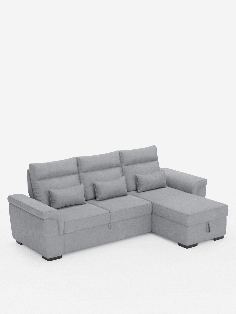 Il divano letto angolare Ischia con schienali scorrevoli, elemento estraibile e penisola contenitore in tessuto smacchiabile misto lino è un divano componibile a forma di L di colore grigio chiaro, con chaise longue sul lato destro, piedini bassi e tre schienali.