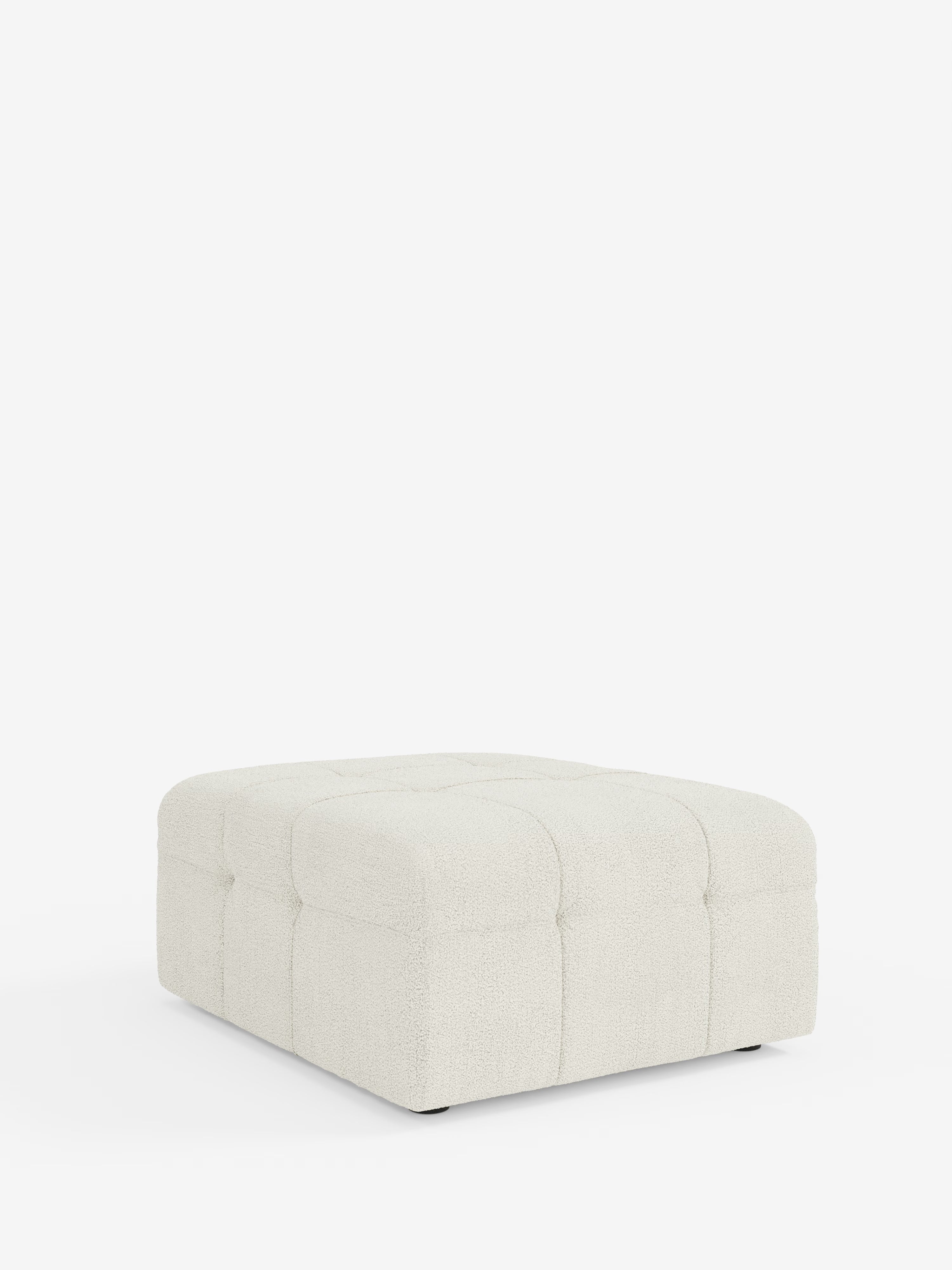 Un pouf quadrato Mosaic e modulo ottoman di Divani.Store, dalle dimensioni di 96x77 cm, è raffigurato su uno sfondo bianco a tinta unita. Rivestito in tessuto bouclé T21 testurizzato e resistente alle macchie, con un motivo capitonné, il pouf presenta bordi delicatamente arrotondati e cuciture a vista che dividono la parte superiore e i lati in quadrati.