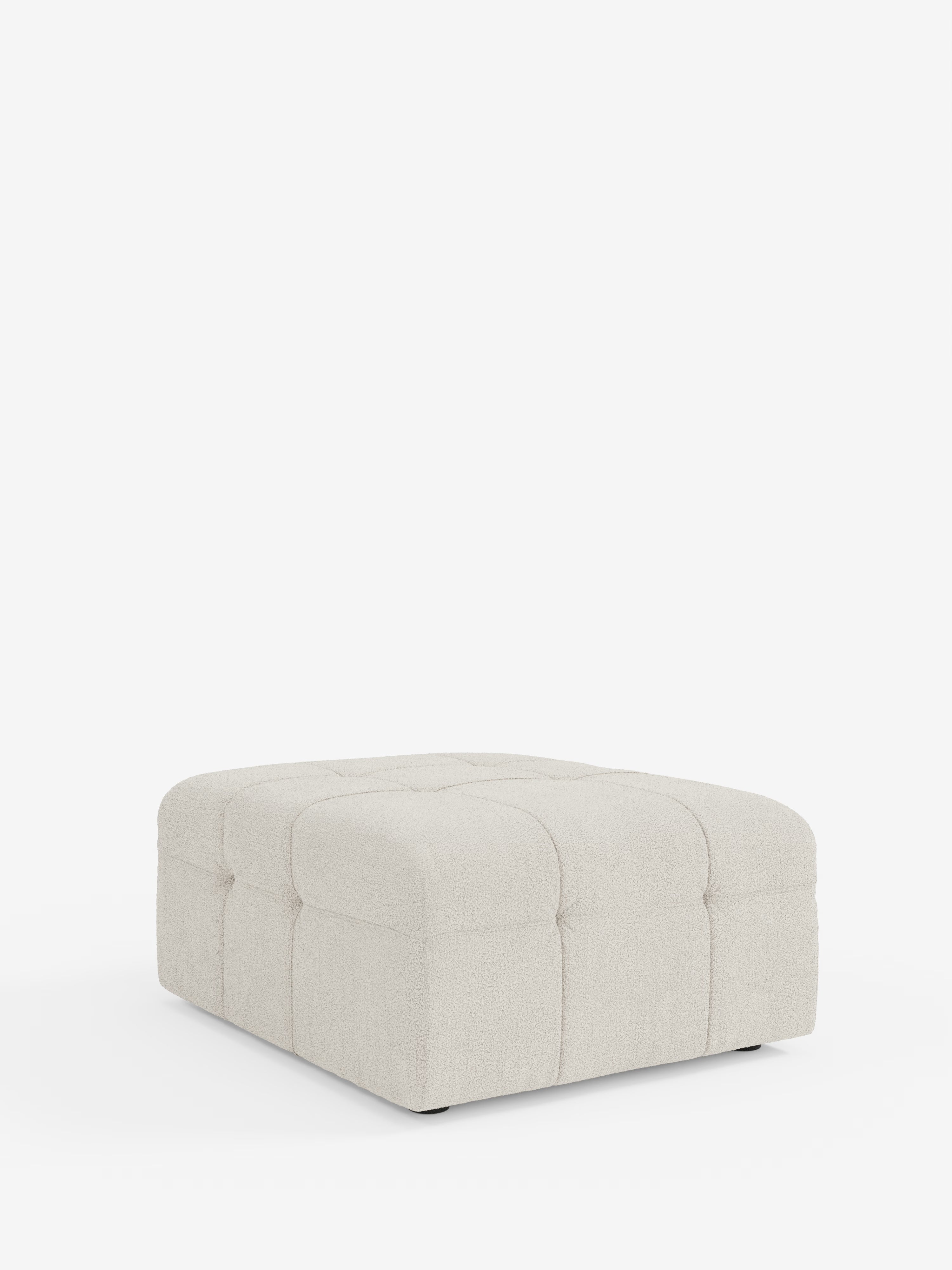 Il pouf e modulo Mosaic in bouclé di Divani.Store presenta una silhouette quadrata color beige chiaro, dalle dimensioni di 96x77 cm, con morbidi bordi arrotondati e una delicata trapuntatura capitonné che forma un motivo a griglia sui lati e sulla parte superiore in tessuto T21 resistente alle macchie. Appoggiato direttamente su una base bianca senza gambe a vista, questo pouf incarna il minimalismo moderno.