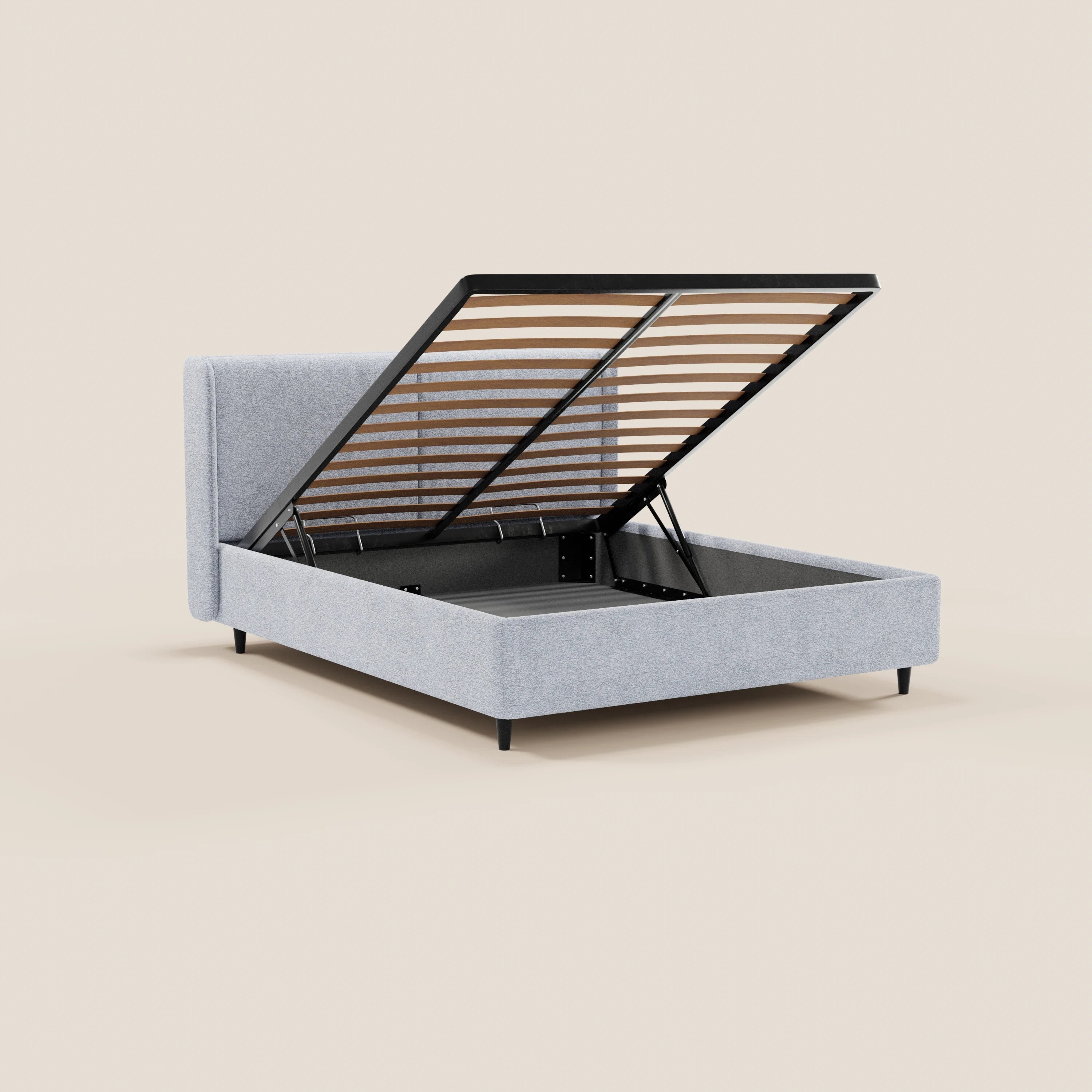 Il letto di design VALKIRIA di Letti.store, realizzato in tessuto grigio chiaro certificato Oeko-Tex® con testiera alta avvolgente e gambe nere, è dotato di una rete a doghe sollevabile che rivela uno spazio contenitore nascosto, come si vede nella foto su sfondo beige a tinta unita.
