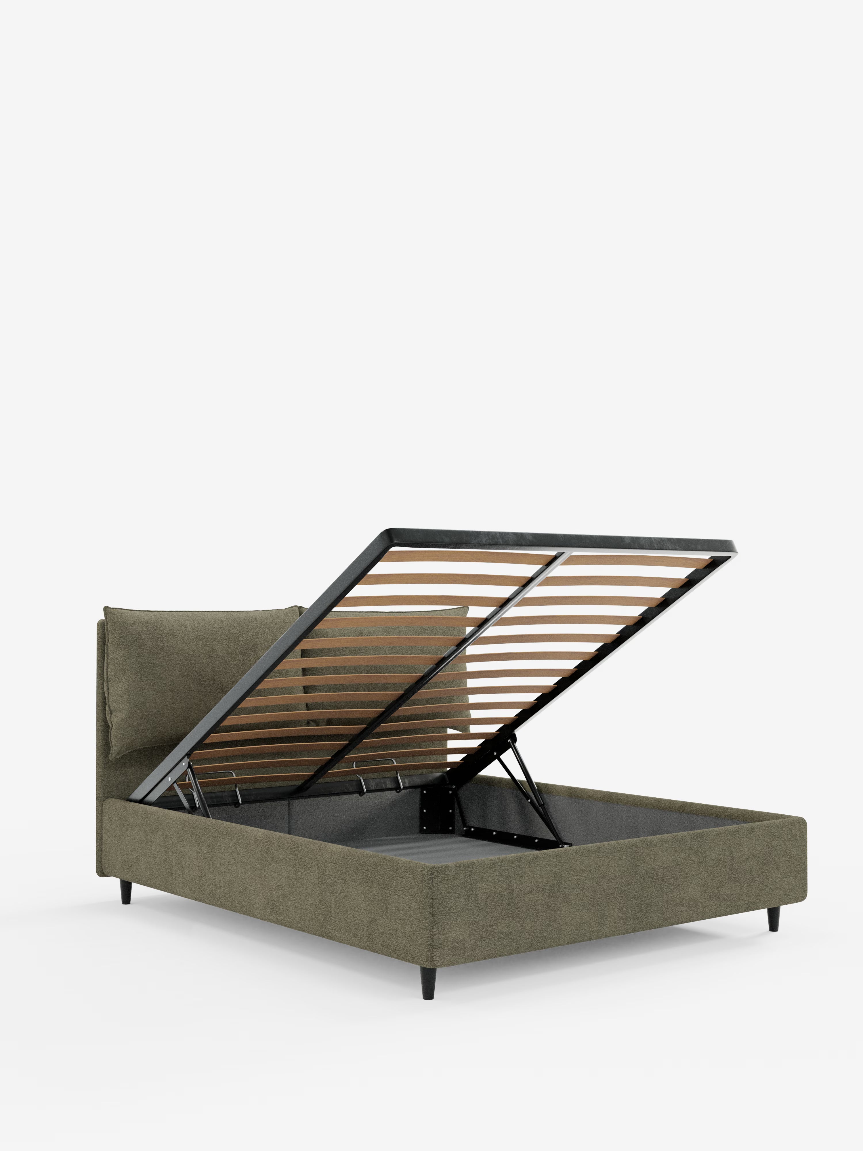 Un letto imbottito ZAYRON in stile contemporaneo di Letti.store, color verde oliva, caratterizzato da gambe nere angolate, una base a doghe apribile con un ampio vano contenitore sottostante e morbidi cuscini regolabili sulla testiera imbottita — il tutto realizzato in tessuto certificato Oeko-Tex®. Presentato su uno sfondo bianco a tinta unita.