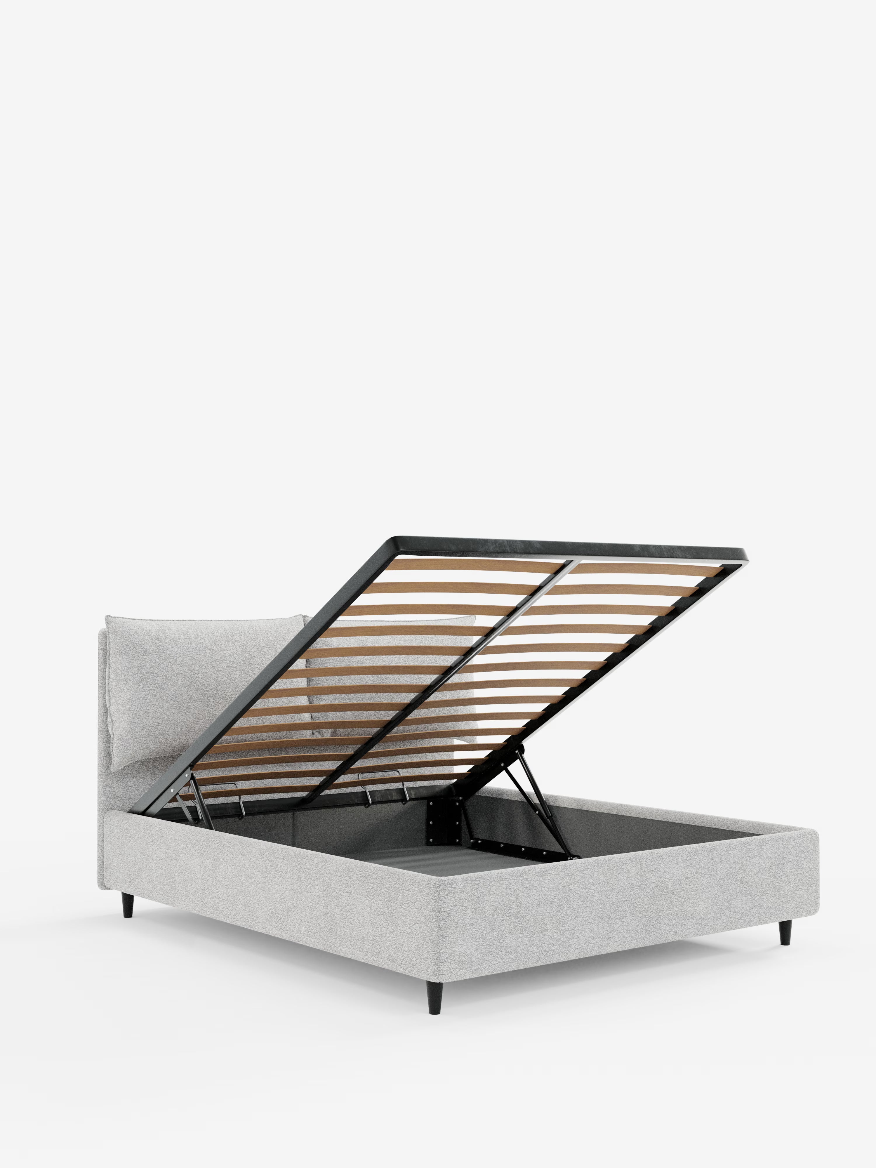 Un moderno letto imbottito ZAYRON con contenitore di Letti.store, rivestito in tessuto grigio chiaro certificato Oeko-Tex®, con gambe corte nere e cuscini morbidi regolabili. Immaginato su uno sfondo bianco a tinta unita con la rete a doghe sollevata ad angolo per rivelare l’ampio vano contenitore sottostante.