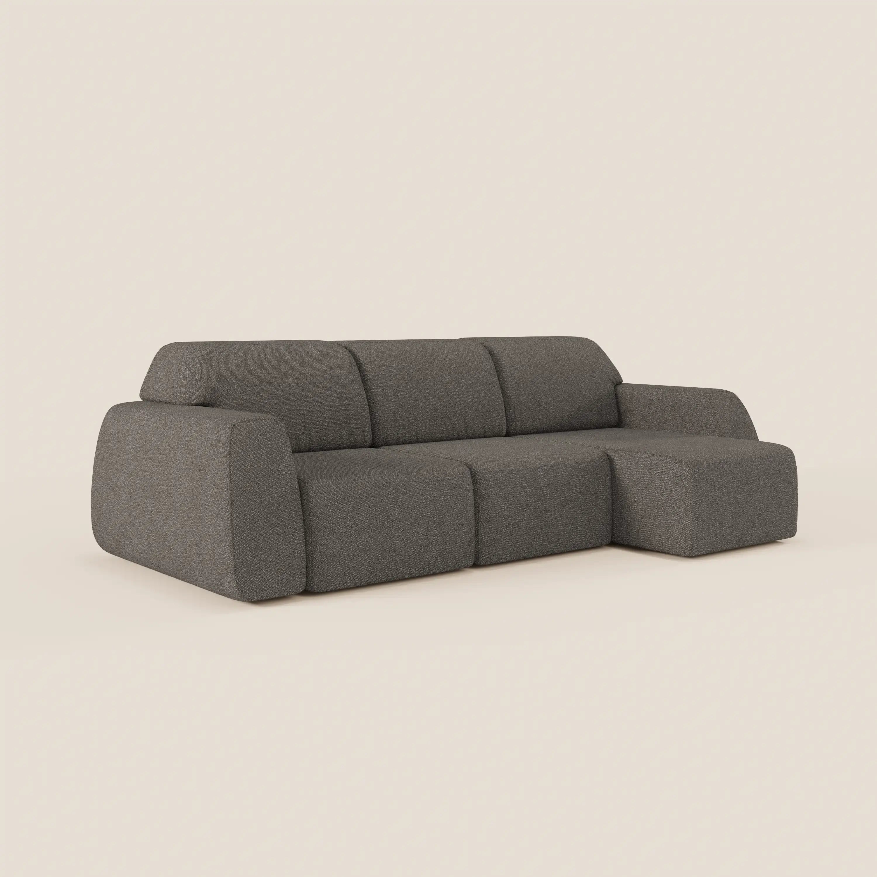 The Divani.Store Orbit angolare con penisola reversibile, tutte le sedute allungabili, in tessuto smacchiabile effetto cotone T33, grigio scuro con bordi arrotondati e schienale basso, su sfondo beige chiaro.