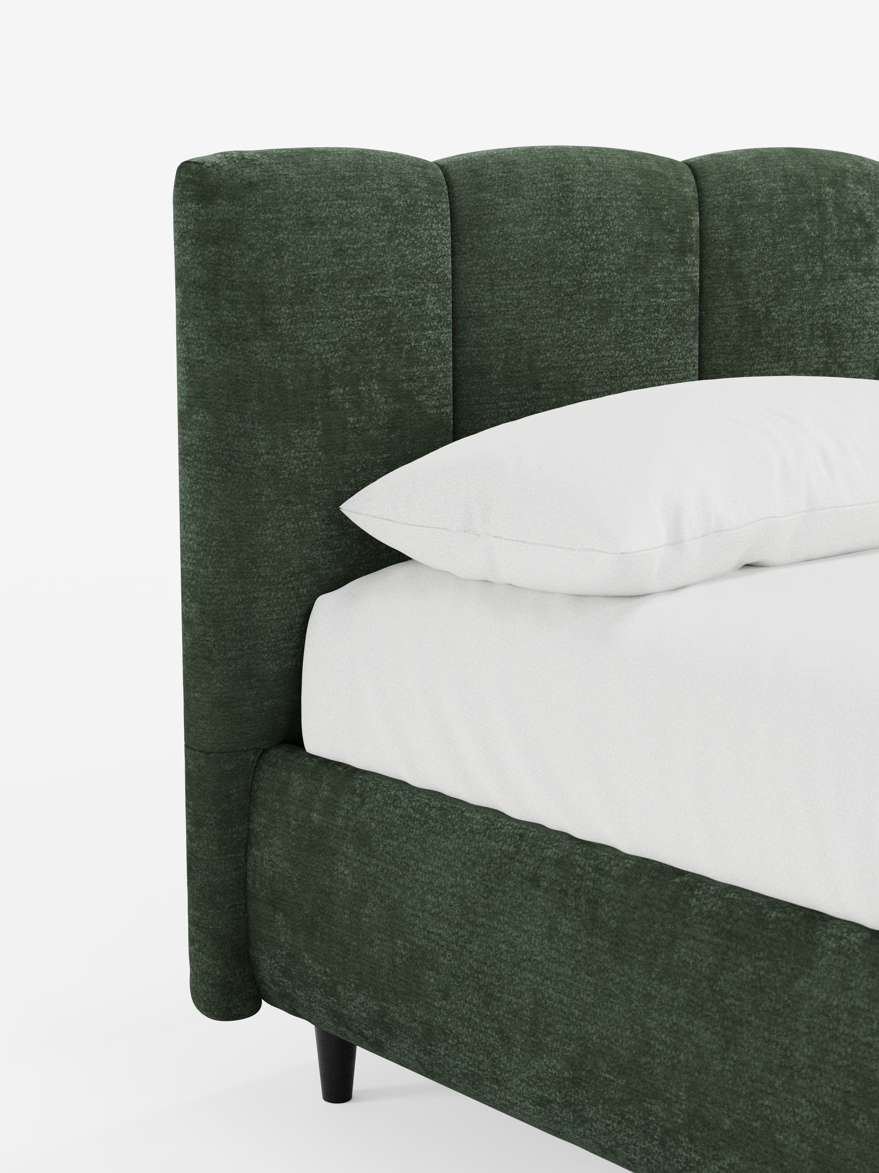 Il letto imbottito ARKAM con contenitore e testiera a cuciture verticali di Letti.store si distingue per il suo design elegante, grazie alla struttura imbottita in verde scuro certificata Oeko-Tex® e alla testiera curva con cuciture verticali. Il letto è presentato con cura, con biancheria da letto e cuscini bianchi appoggiati su gambe corte e nere che ne esaltano l’aspetto slanciato, il tutto su uno sfondo bianco a tinta unita.