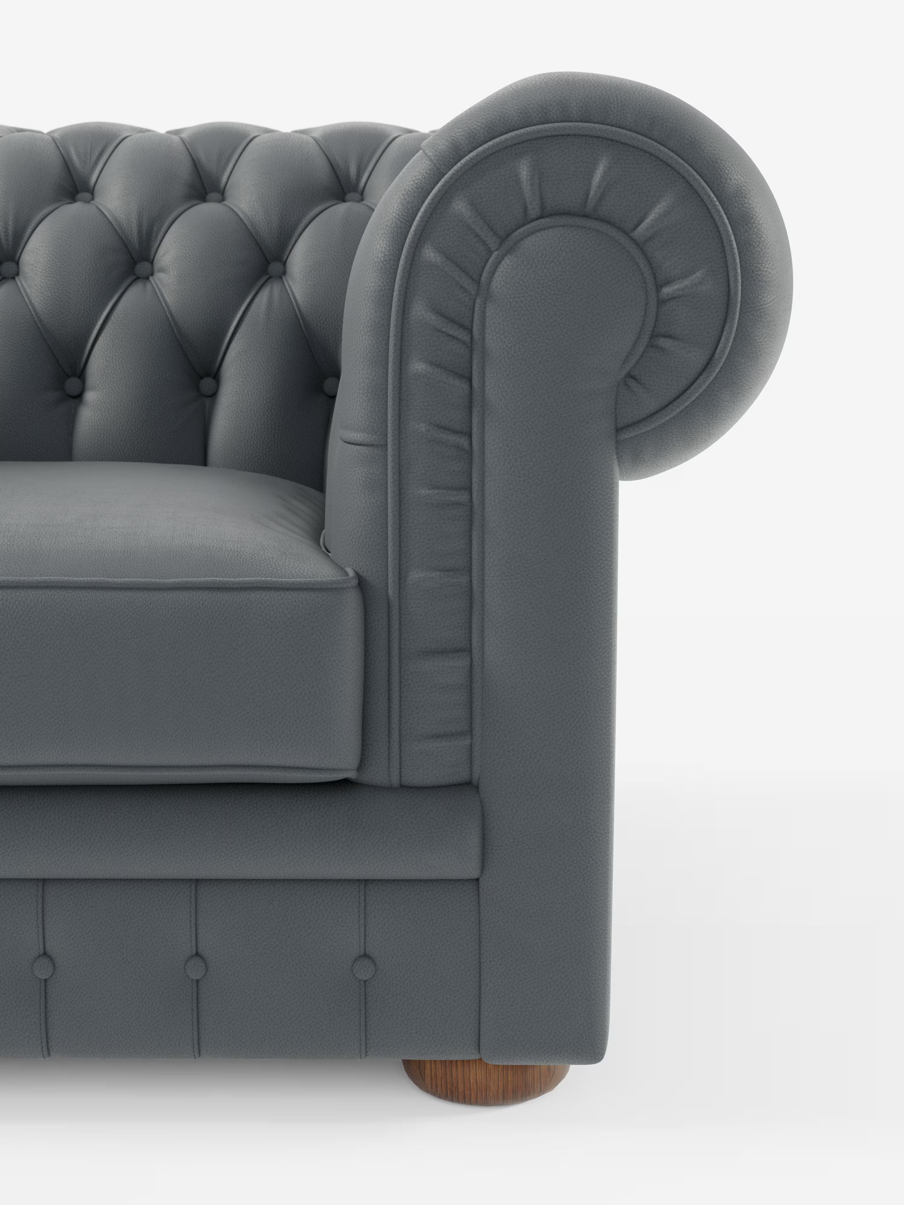 Primo piano della poltrona Chester in vera pelle spessorata con capitonné artigianale di Divani.Store, che mette in risalto il bracciolo in pelle capitonné grigio scuro dal design arrotondato, il morbido cuscino di seduta, i dettagli artigianali del capitonné a bottoni profondi e una gamba rotonda in legno, il tutto su sfondo bianco. È visibile solo una parte della parte frontale e laterale del divano.