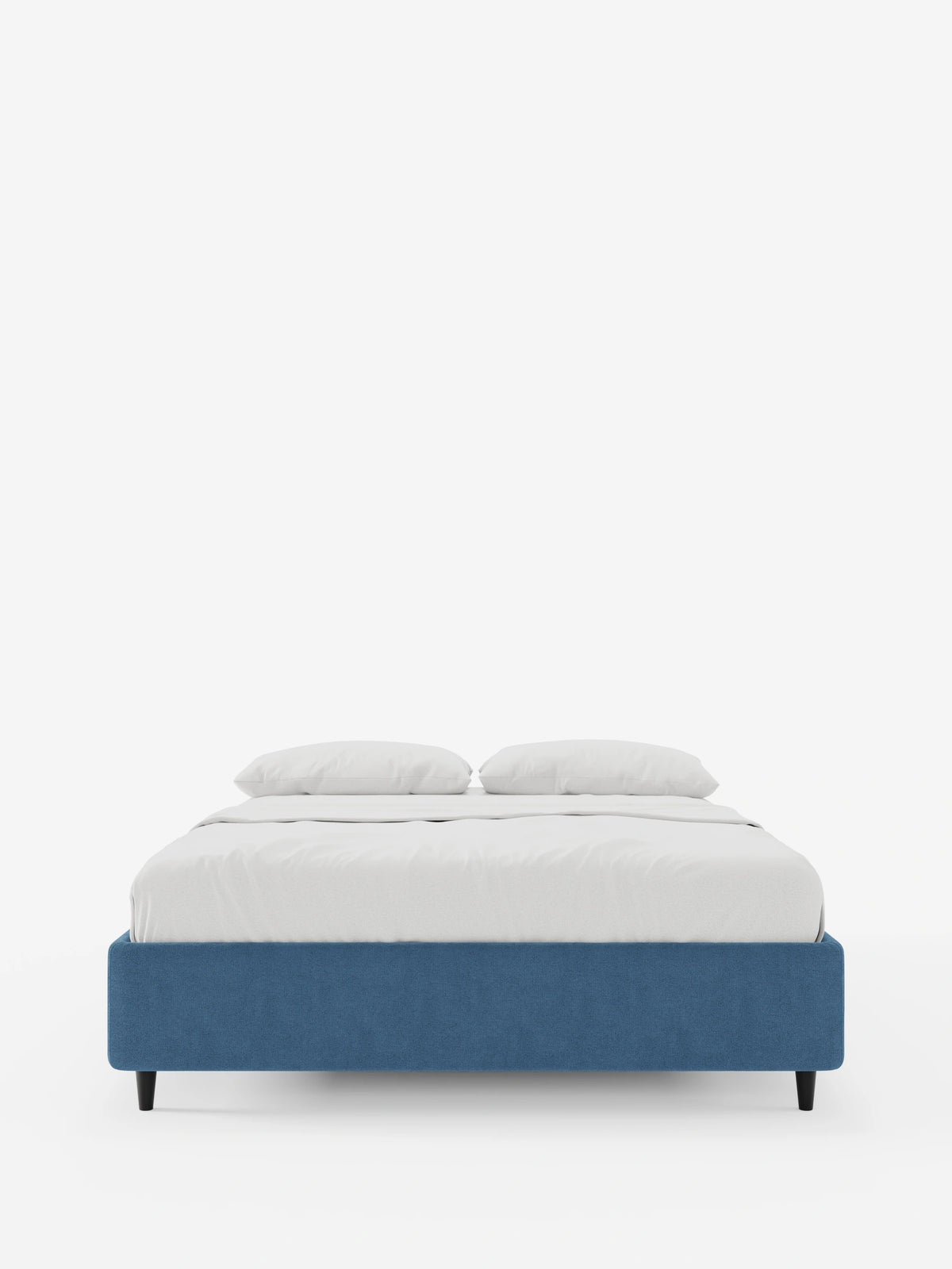 Il letto sommier imbottito ERON con contenitore in tessuto impermeabile certificato Oeko-Tex è una struttura da letto dal profilo basso, di colore blu intenso, con sottili gambe nere, rivestita con lenzuola bianche immacolate e due cuscini su uno sfondo bianco a tinta unita.