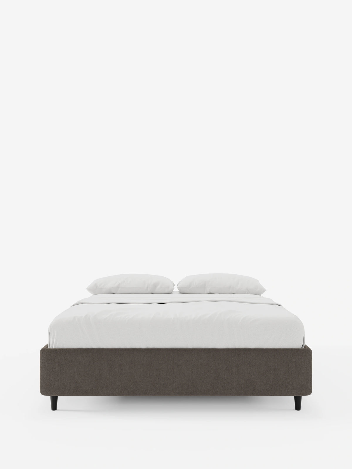 Un letto sommier ERON di colore grigio scuro, dal profilo ribassato, imbottito e dotato di vano contenitore in tessuto impermeabile certificato Oeko-Tex, dal design minimalista, rivestito con biancheria da letto bianca, su gambe corte nere, su uno sfondo bianco a tinta unita.