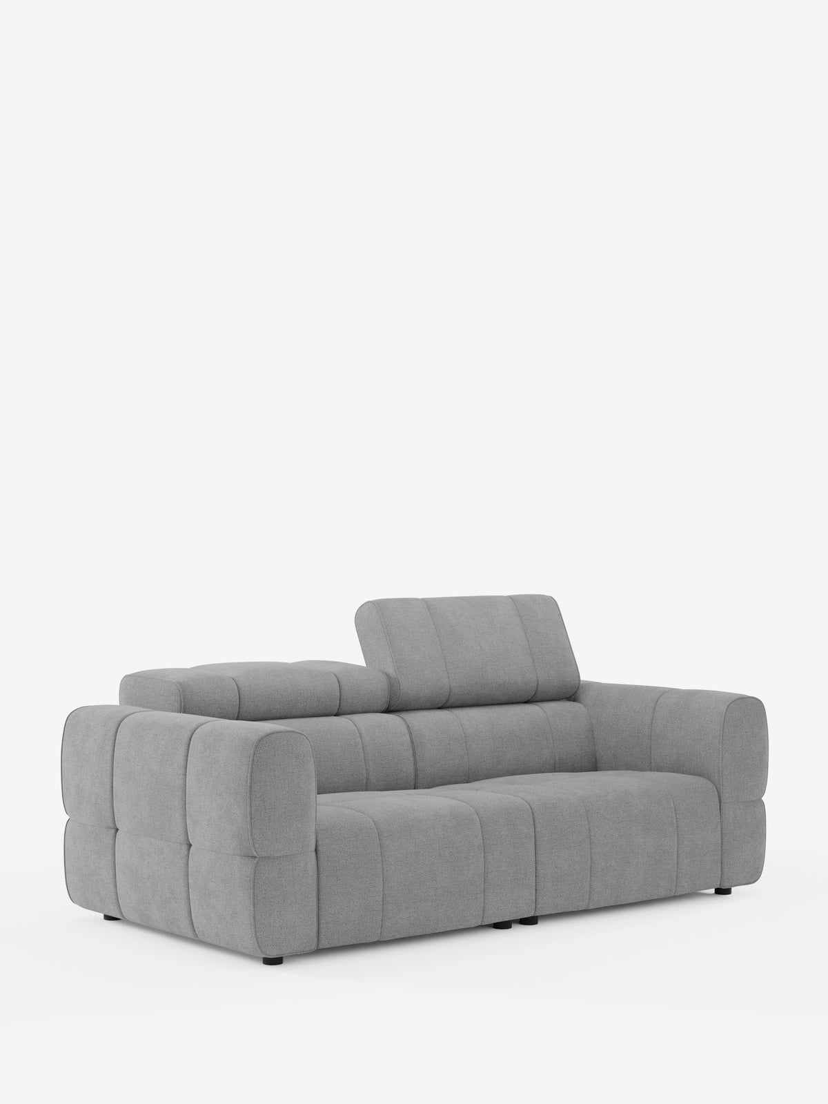 Un divano modulare Giotto grigio chiaro a 3 posti, con poggiatesta reclinabili e funzione relax elettrica opzionale, rivestito in tessuto smacchiabile T23 con motivo a griglia trapuntato; uno dei poggiatesta è sollevato e il divano poggia su piccoli piedini scuri su uno sfondo bianco.