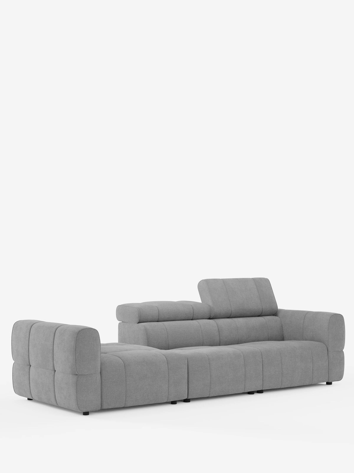 Un divano componibile Giotto di colore grigio chiaro con terminale aperto - opzione relax elettrico in tessuto smacchiabile T23 con motivo trapuntato, ampio terminale sinistro aperto e poggiatesta regolabile, in primo piano su uno sfondo bianco.