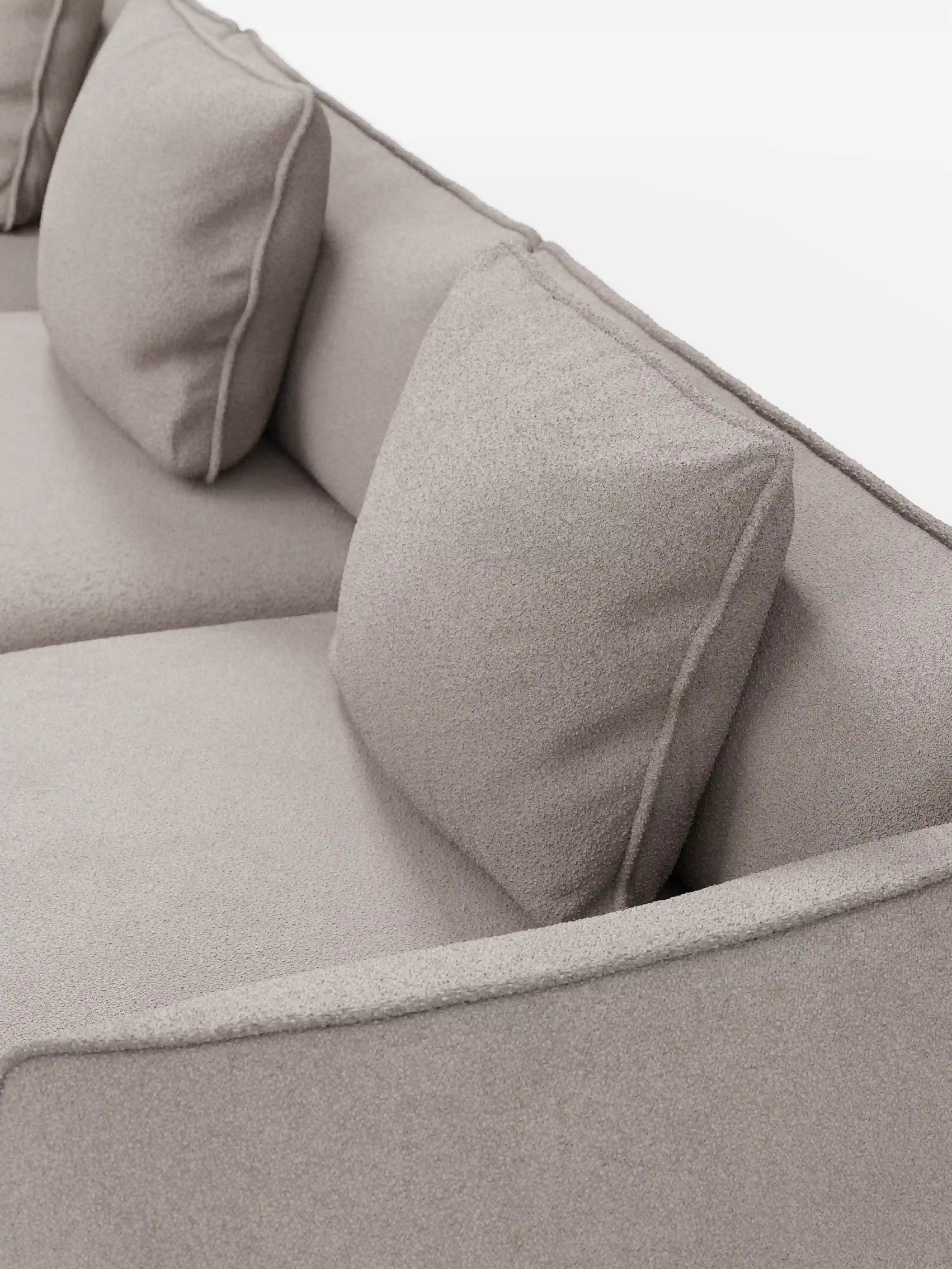 Primo piano del divano modulare a 3 posti Nimbus, realizzabile in morbido tessuto smacchiabile effetto cotone T33 di Divani.Store. Questo elegante divano color beige chiaro presenta due cuscini dello schienale quadrati e un bracciolo, con un tessuto morbido e dalla trama delicata che ne esalta il fascino moderno. Su uno sfondo bianco a tinta unita, le sue linee pulite e il design minimalista lo rendono un complemento d’arredo versatile per qualsiasi ambiente.