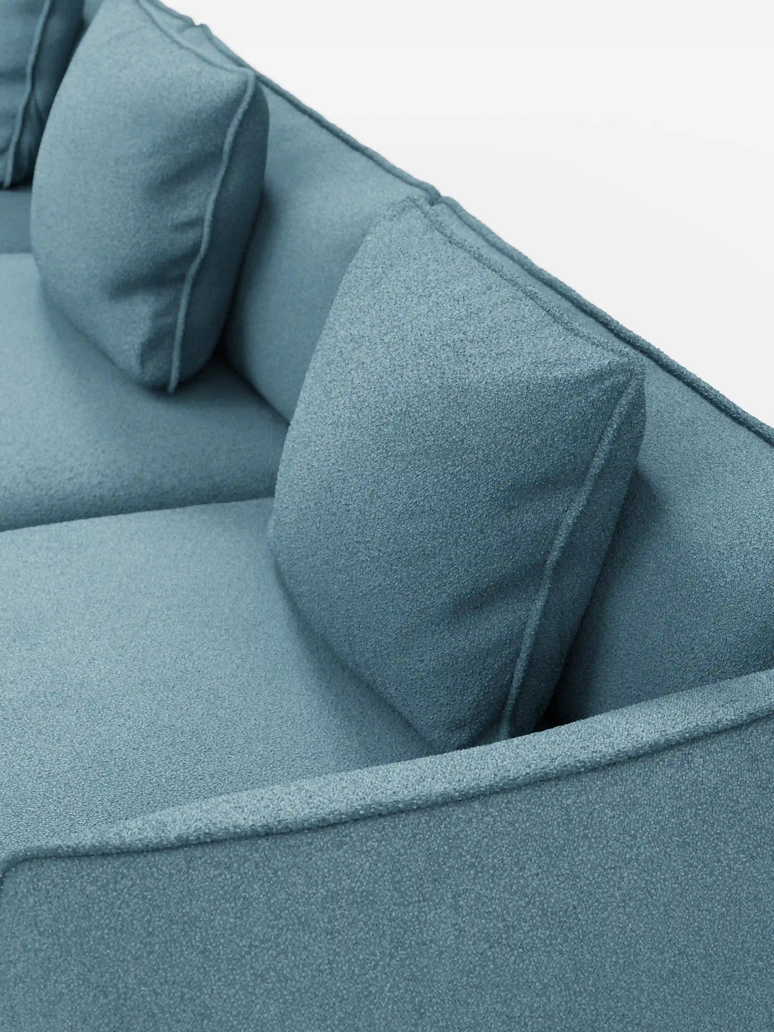 Primo piano del divano modulare a 3 posti Nimbus, realizzabile in morbido tessuto smacchiabile effetto cotone T33 di Divani.Store, caratterizzato da due grandi cuscini quadrati appoggiati allo schienale. Il morbido tessuto effetto cotone e i bordi puliti e lineari sottolineano l'estetica moderna del divano. Su uno sfondo bianco a tinta unita, questo divano componibile mette in risalto il suo design elegante e le sue versatili opzioni di seduta.