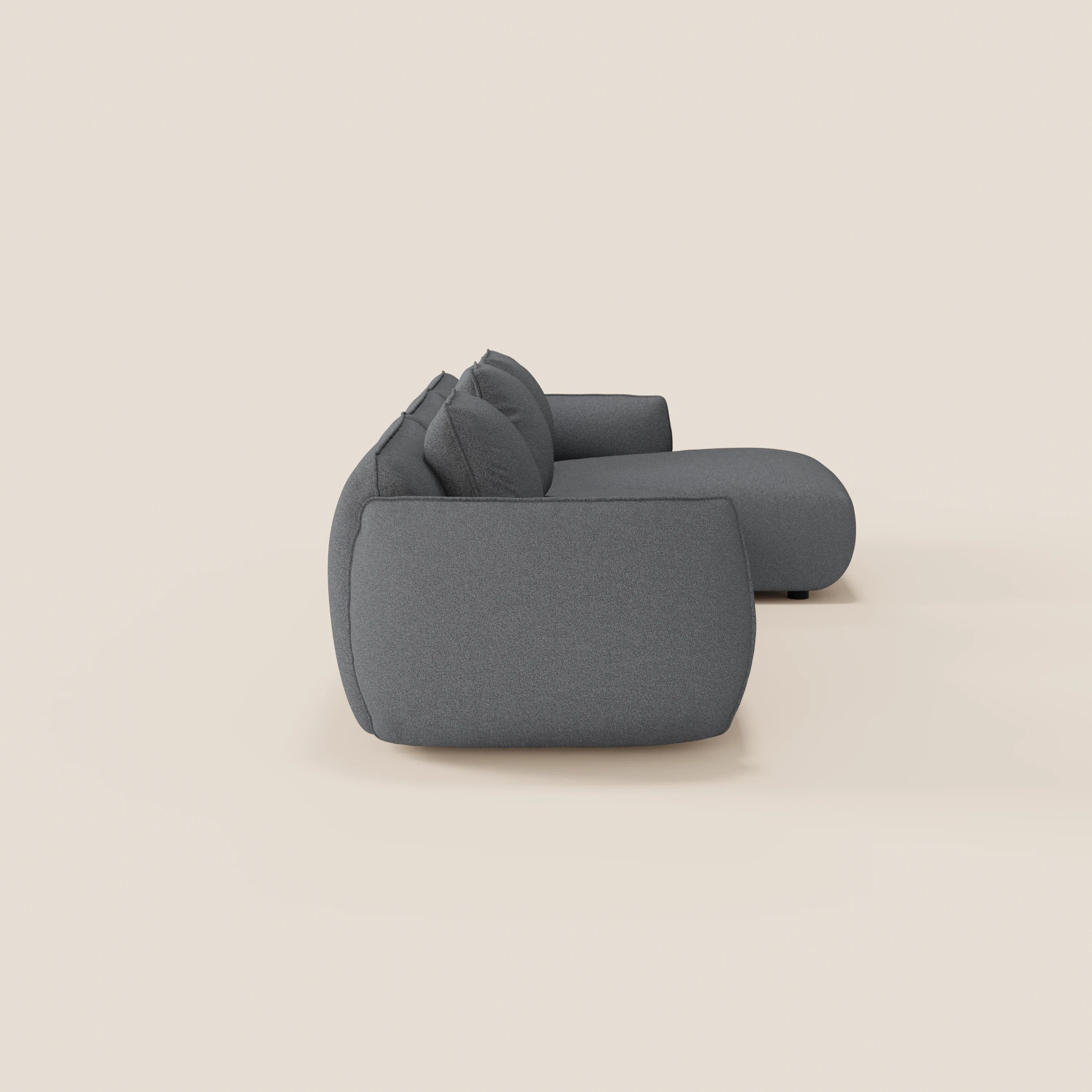 Il divano Nimbus angolare con penisola componibile di Divani.Store, realizzato in morbido tessuto effetto cotone smacchiabile T33, è mostrato di lato su sfondo beige chiaro: linee moderne, spigoli arrotondati e cuscini imbottiti e accoglienti.