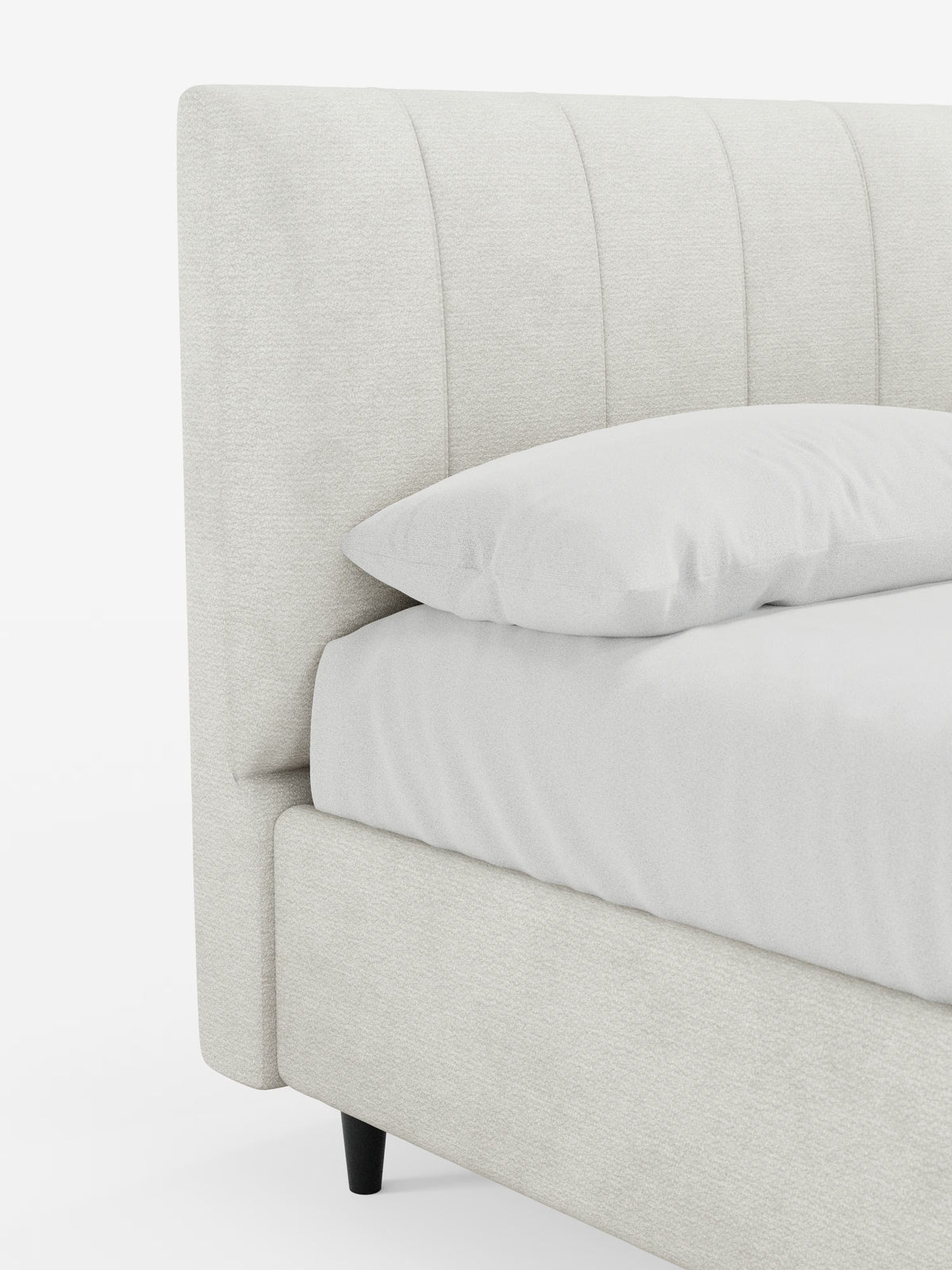 Un primo piano del letto imbottito ONYX con contenitore e testiera verticale in tessuto certificato Oeko-Tex® di Letti.store, che mette in risalto la testiera imbottita a pannelli verticali e la sponda laterale abbinata color beige chiaro. Il lenzuolo e il cuscino, sistemati con cura, riprendono le morbide tonalità del beige, mentre nella parte inferiore si intravede una gamba affusolata nera. Sfondo bianco.