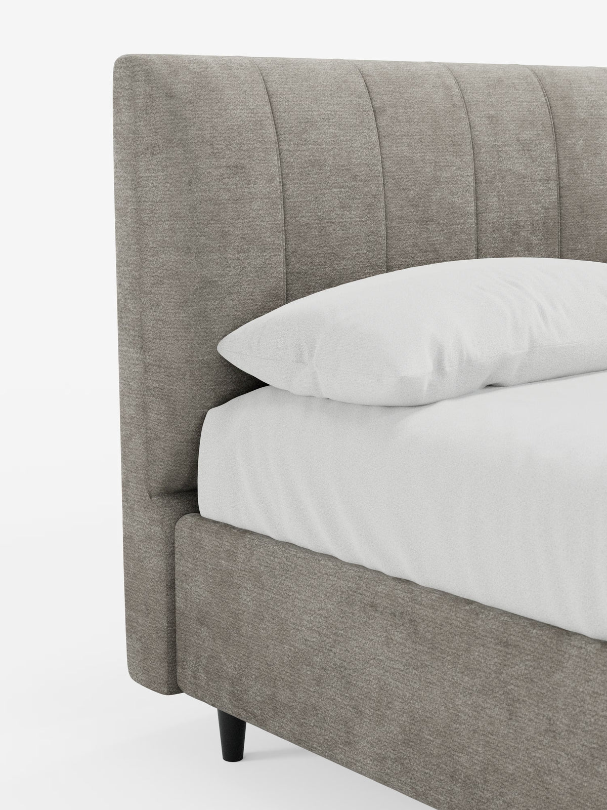 Un primo piano di un angolo del letto che mostra il modello ONYX, letto imbottito con contenitore e testiera verticale in tessuto certificato Oeko-Tex® di Letti.store, con la sua alta testiera grigia cucita verticalmente, la biancheria da letto di un bianco candido e un cuscino bianco. Questo elegante letto moderno presenta gambe corte nere ed è posizionato su uno sfondo bianco a tinta unita.