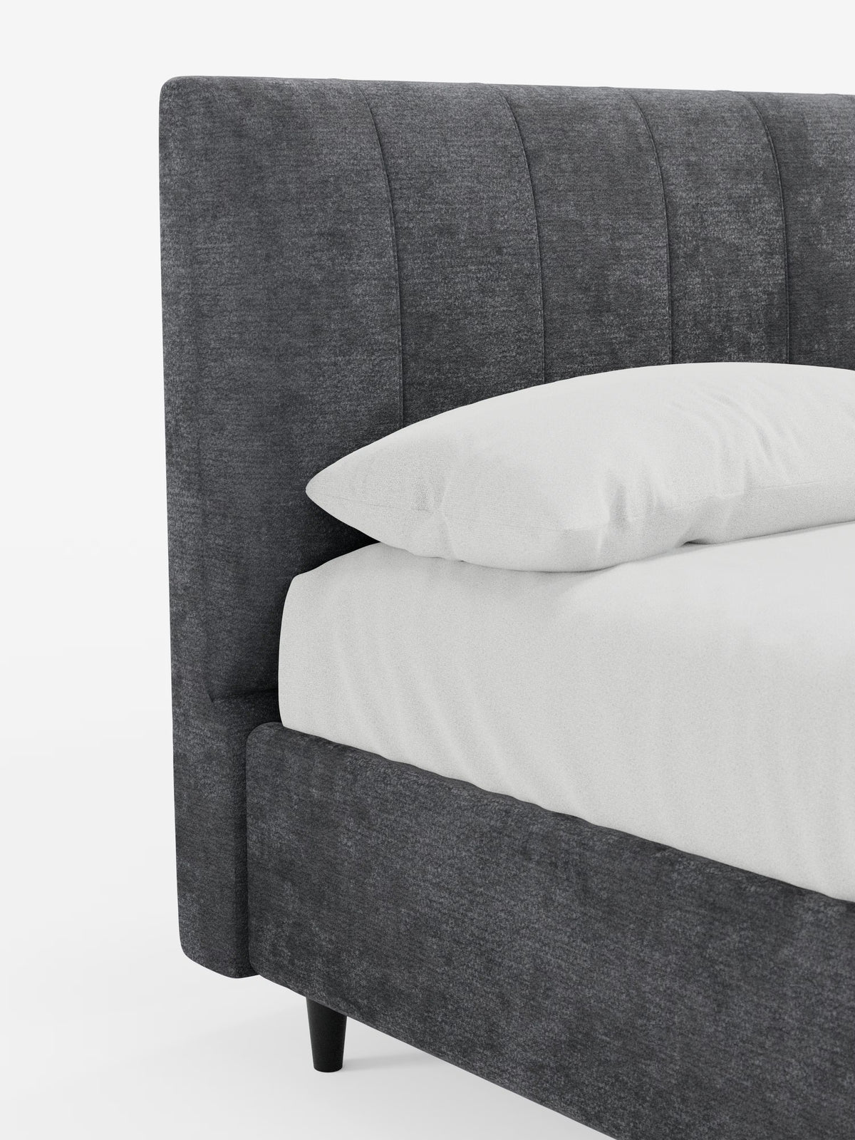 Un primo piano del letto imbottito ONYX con contenitore e testiera verticale in tessuto certificato Oeko-Tex® di Letti.store, che ne mette in risalto il design moderno con una testiera imbottita grigio scuro e una struttura caratterizzata da sottili cuciture verticali. Il letto è abbinato a un cuscino bianco e a un lenzuolo con angoli, poggia su corte gambe nere ed è posto su uno sfondo bianco a tinta unita.