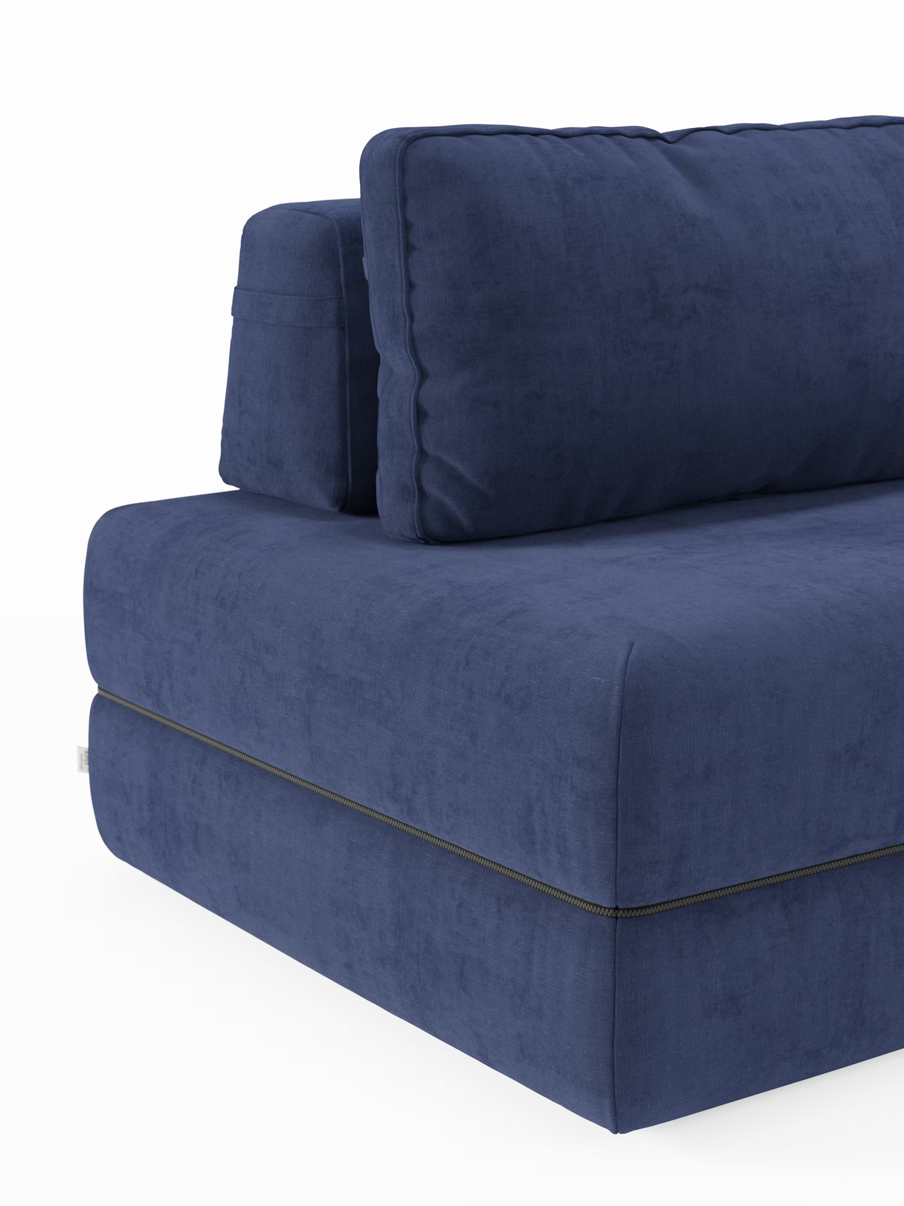 Un primo piano del divano letto matrimoniale Rift a 2 e 3 posti con schienali mobili di Divani.Store, in tessuto blu navy. Questo moderno divano letto è caratterizzato da spessi cuscini di seduta e schienale rivestiti in un tessuto dalla trama delicata, che uniscono stile e comfort. Dotato di un materasso in memory foam di alta qualità, alto 22 cm, nella versione T31, garantisce un sonno riposante. Sul lato è visibile una piccola etichetta in tessuto, mentre lo sfondo è bianco a tinta unita.