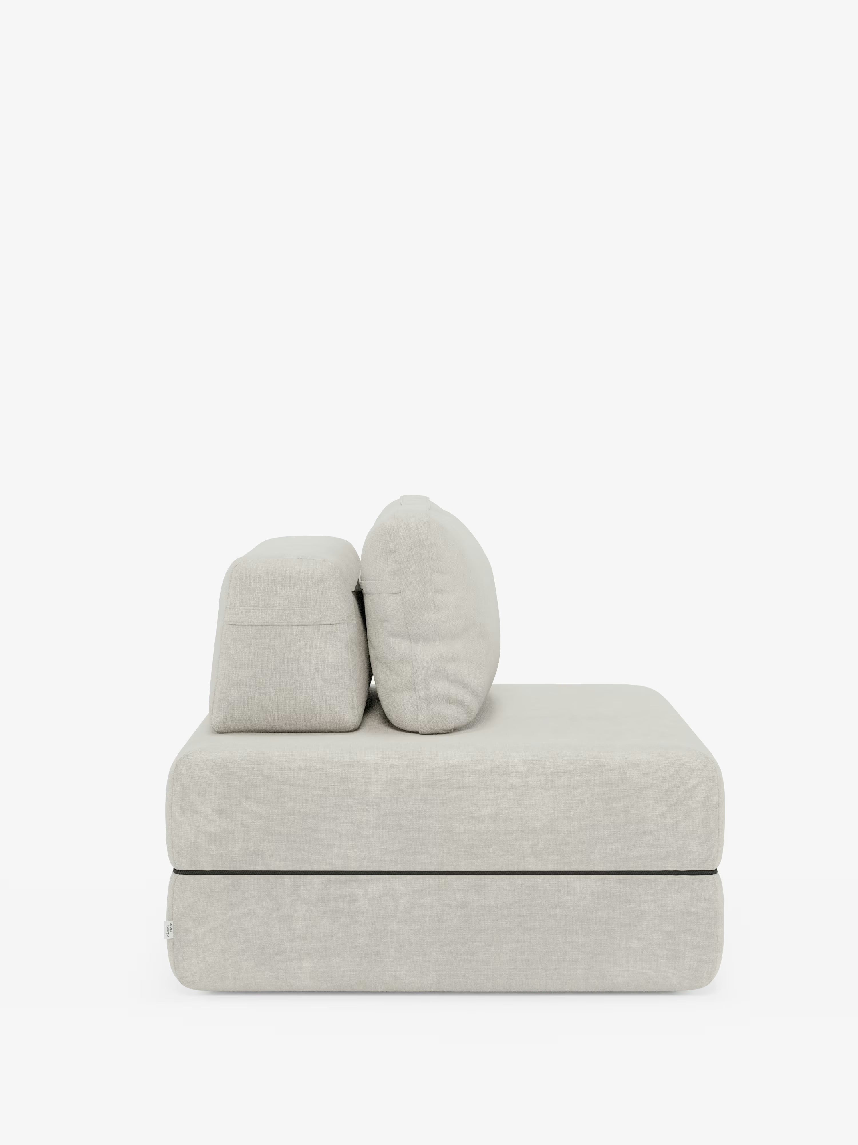 Una poltrona letto Rift di Divani.Store, dal design minimalista e in grigio chiaro, dotata di un materasso in memory foam alto 24 cm e di uno schienale mobile, si staglia su uno sfondo bianco liscio. Il rivestimento in morbido e lussuoso tessuto T31 antimacchia si abbina perfettamente alla silhouette moderna e slanciata, caratterizzata da linee pulite e bordi arrotondati, incarnando il comfort contemporaneo e l’elegante semplicità.