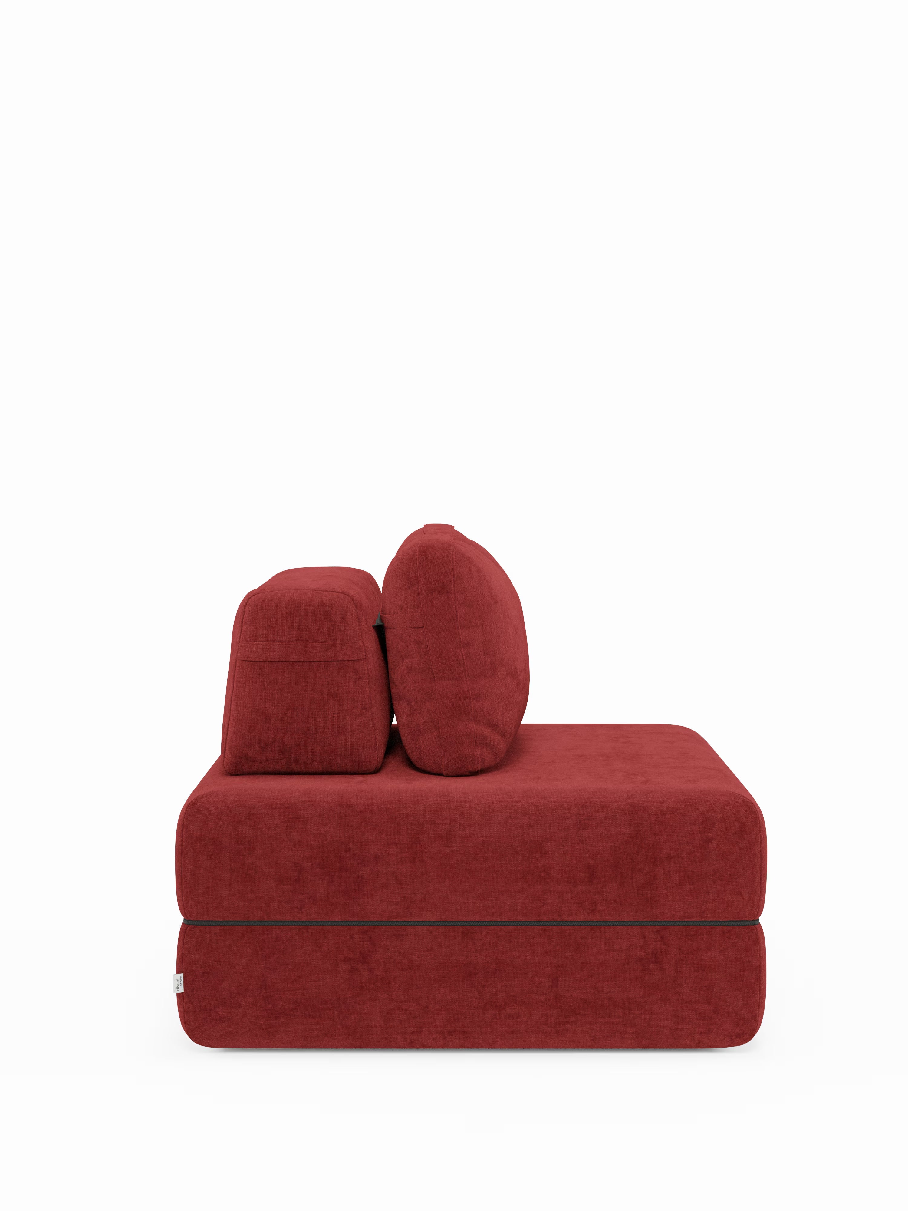 Vista laterale della poltrona letto Rift di Divani.Store, rivestita in tessuto T31 rosso intenso, resistente alle macchie e dalla morbida consistenza vellutata. Questa poltrona moderna senza braccioli presenta due cuscini quadrati sullo schienale e una seduta rettangolare spessa dal design minimalista e squadrato. La struttura versatile comprende uno schienale regolabile e un materasso in memory foam integrato alto 22 cm, il tutto su uno sfondo bianco a tinta unita.
