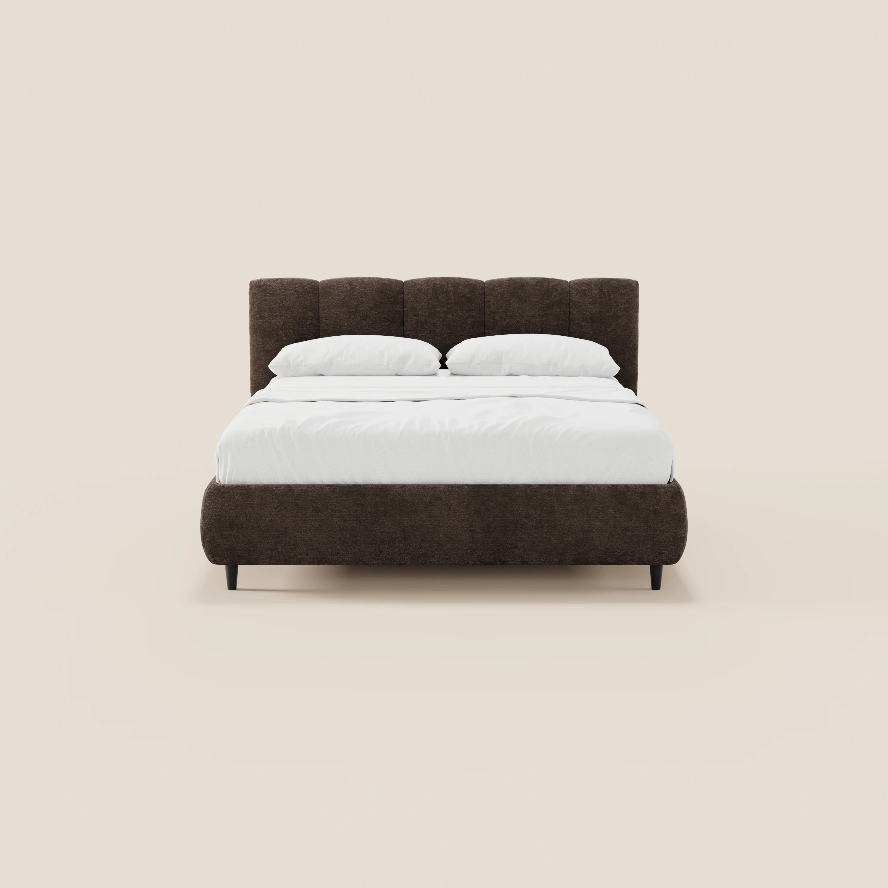 Il letto imbottito ARKAM di Letti.store presenta una testiera alta con cuciture verticali in tessuto certificato Oeko-Tex®, finitura marrone scuro, biancheria da letto e cuscini bianchi e gambe corte nere: perfetto per una camera da letto in stile shabby chic.