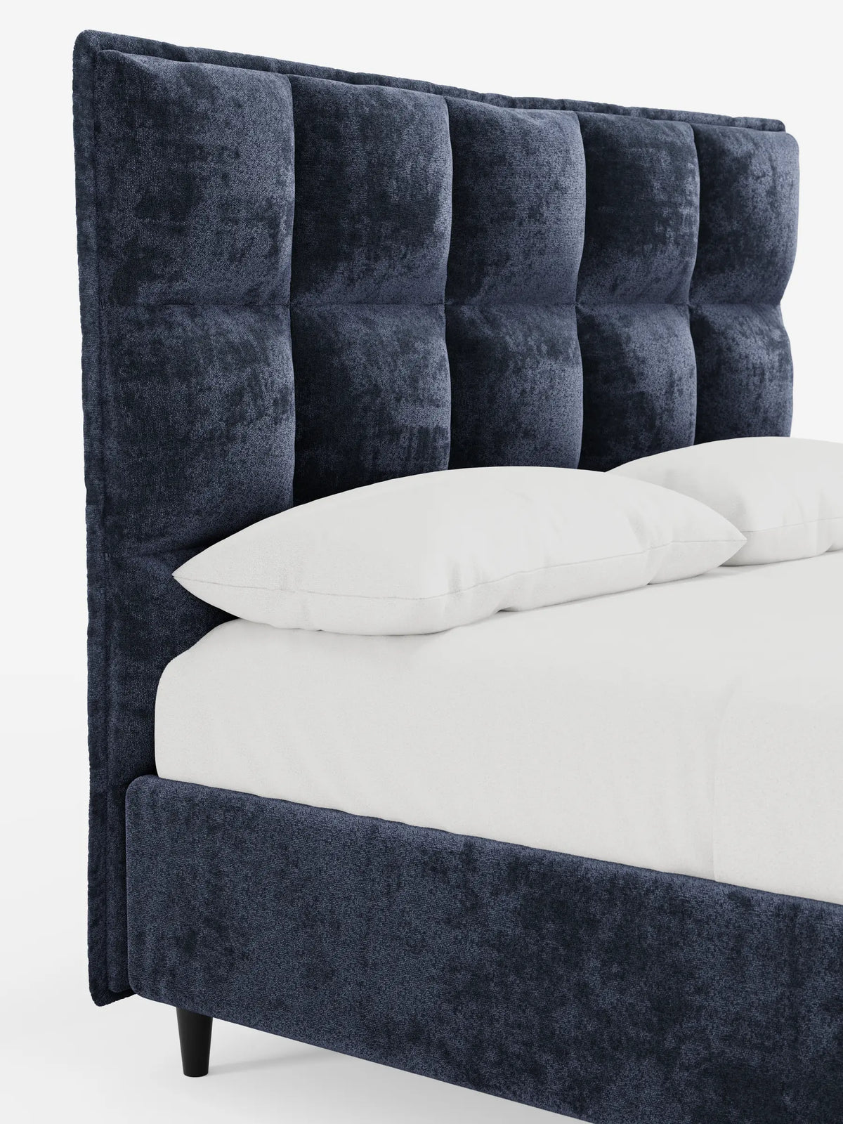 Un letto imbottito AURO con contenitore e testiera alta capitonné in ciniglia Oeko-Tex® in velluto blu navy, caratterizzato da una testiera alta capitonné, biancheria da letto bianca e gambe affusolate scure su sfondo bianco.
