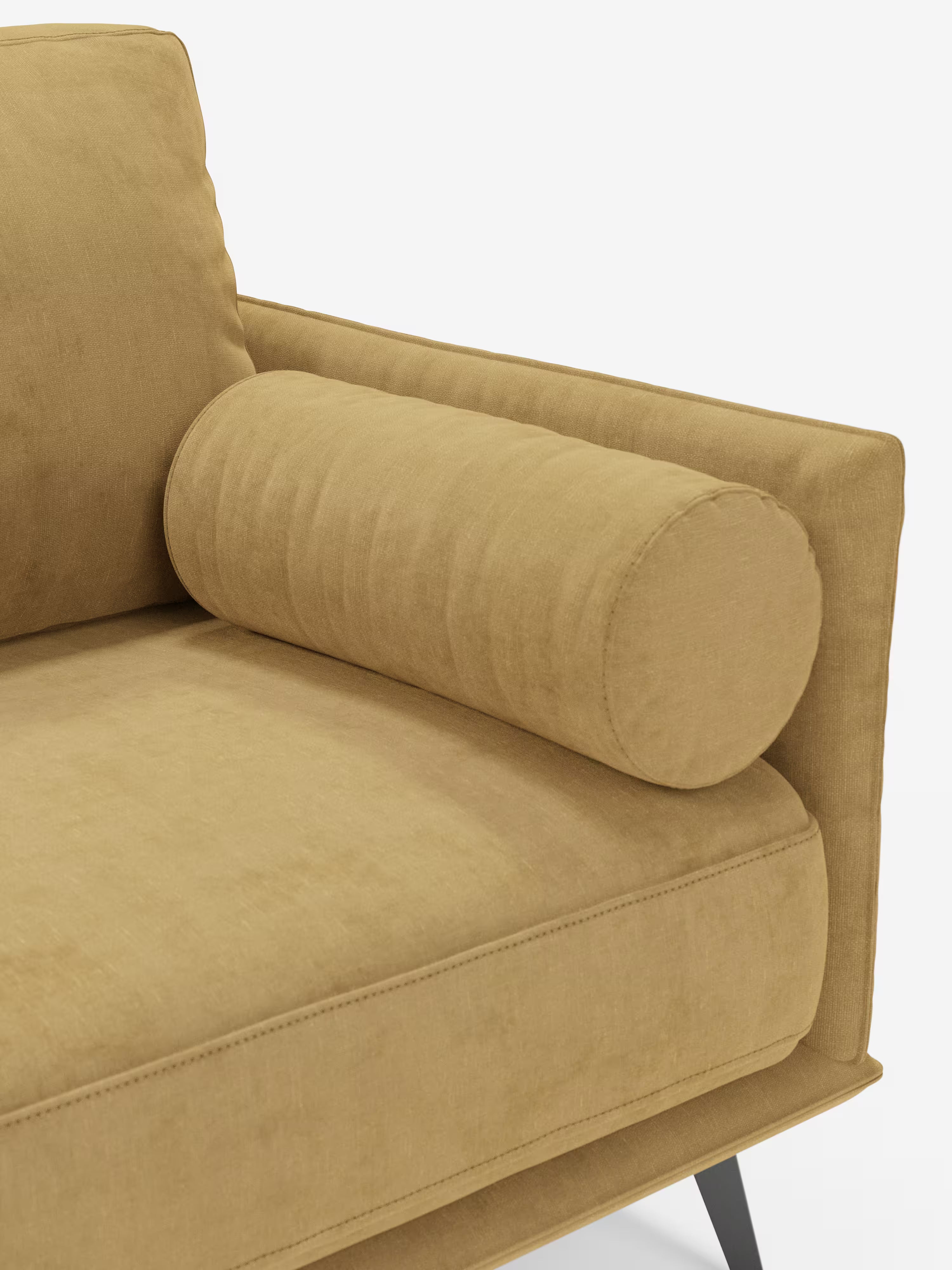 Un primo piano del bracciolo destro del divano Basalto, modello lineare a 2 o 3 posti con seduta unica e base in metallo, rivestito in tessuto smacchiabile T31 di Divani.Store, in velluto giallo senape. Questo divano minimalista presenta un cuscino rettangolare, un cuscino cilindrico e sottili gambe angolate nere con una robusta struttura in metallo. Il tessuto morbido e leggermente testurizzato risalta sullo sfondo bianco a tinta unita.