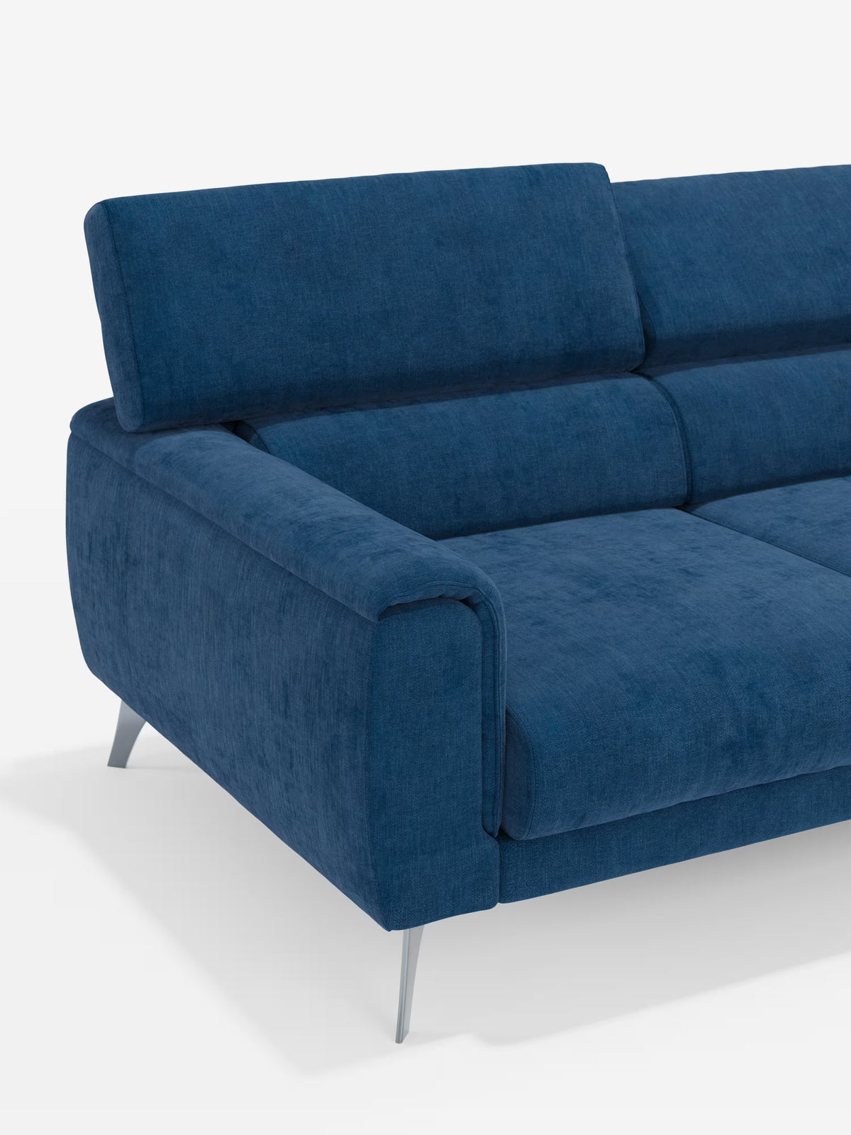 Un primo piano del divano Caravaggio a 4 posti con tre sedute scorrevoli di Divani.Store, rivestito in tessuto smacchiabile T31 blu moderno, dotato di poggiatesta regolabili, ampi braccioli, imbottitura morbida e sottili gambe in metallo. Su uno sfondo bianco a tinta unita è visibile solo la parte sinistra di questo elegante divano moderno.
