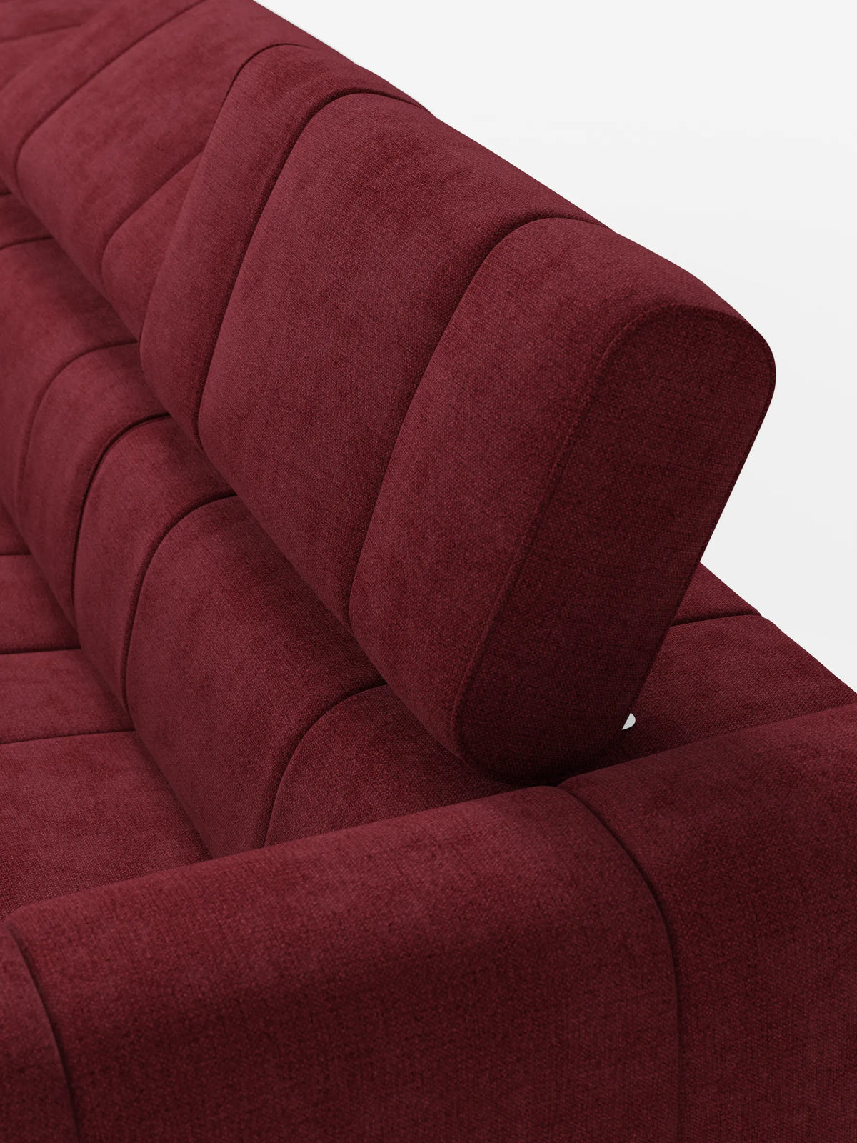 Un primo piano dall'alto di un divano modulare Giotto a 4 posti di colore rosso intenso, con poggiatesta reclinabili e funzione relax elettrica opzionale, rivestito in tessuto smacchiabile T23, caratterizzato da cuciture verticali a canalina e da un poggiatesta regolabile su una superficie bianco sporco.