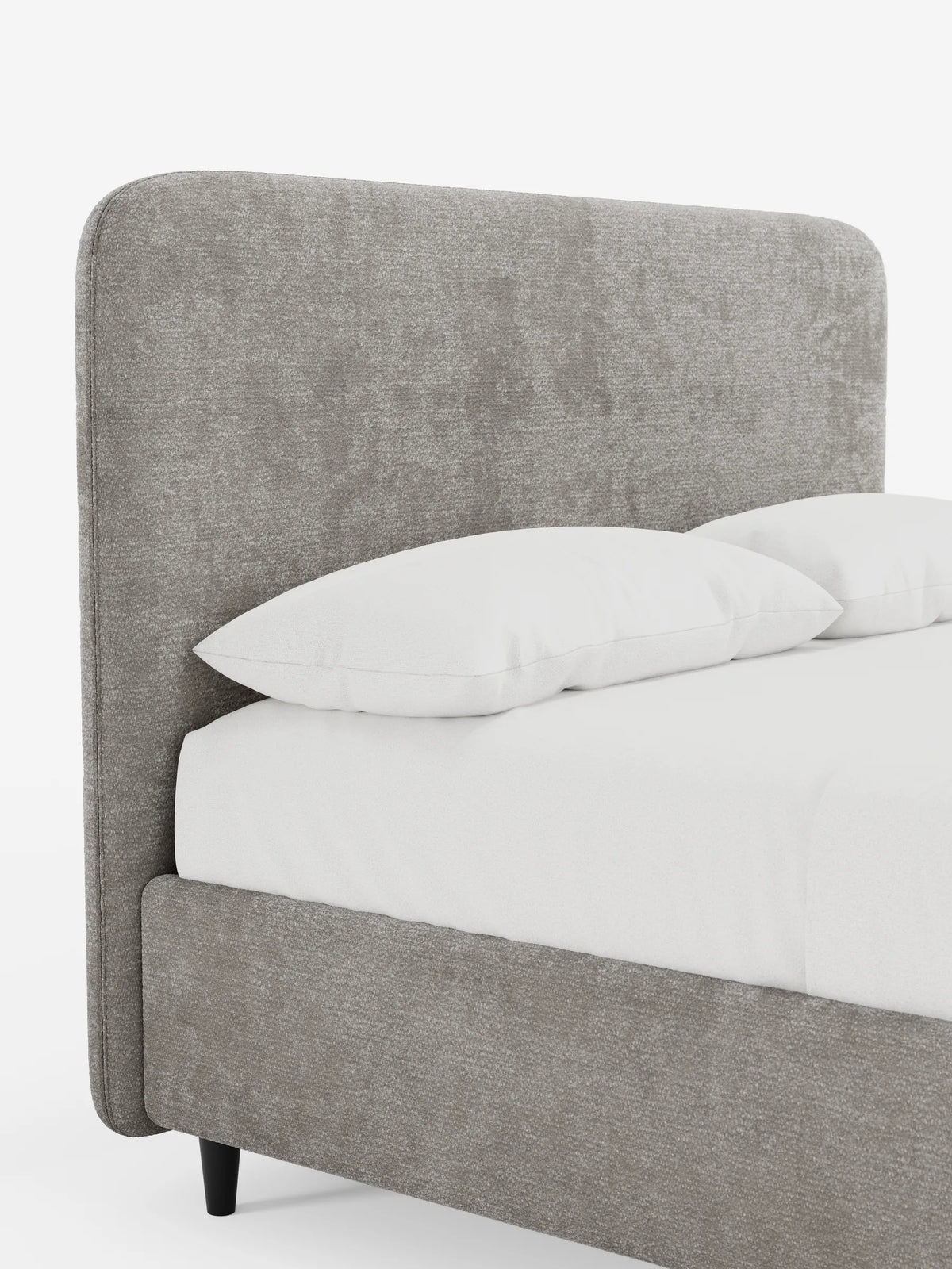 Un primo piano di un letto KAELOS minimal imbottito con una testiera alta e arrotondata in tessuto taupe testurizzato, con lenzuola bianche, due cuscini e gambe corte e affusolate di colore scuro su uno sfondo bianco a tinta unita.