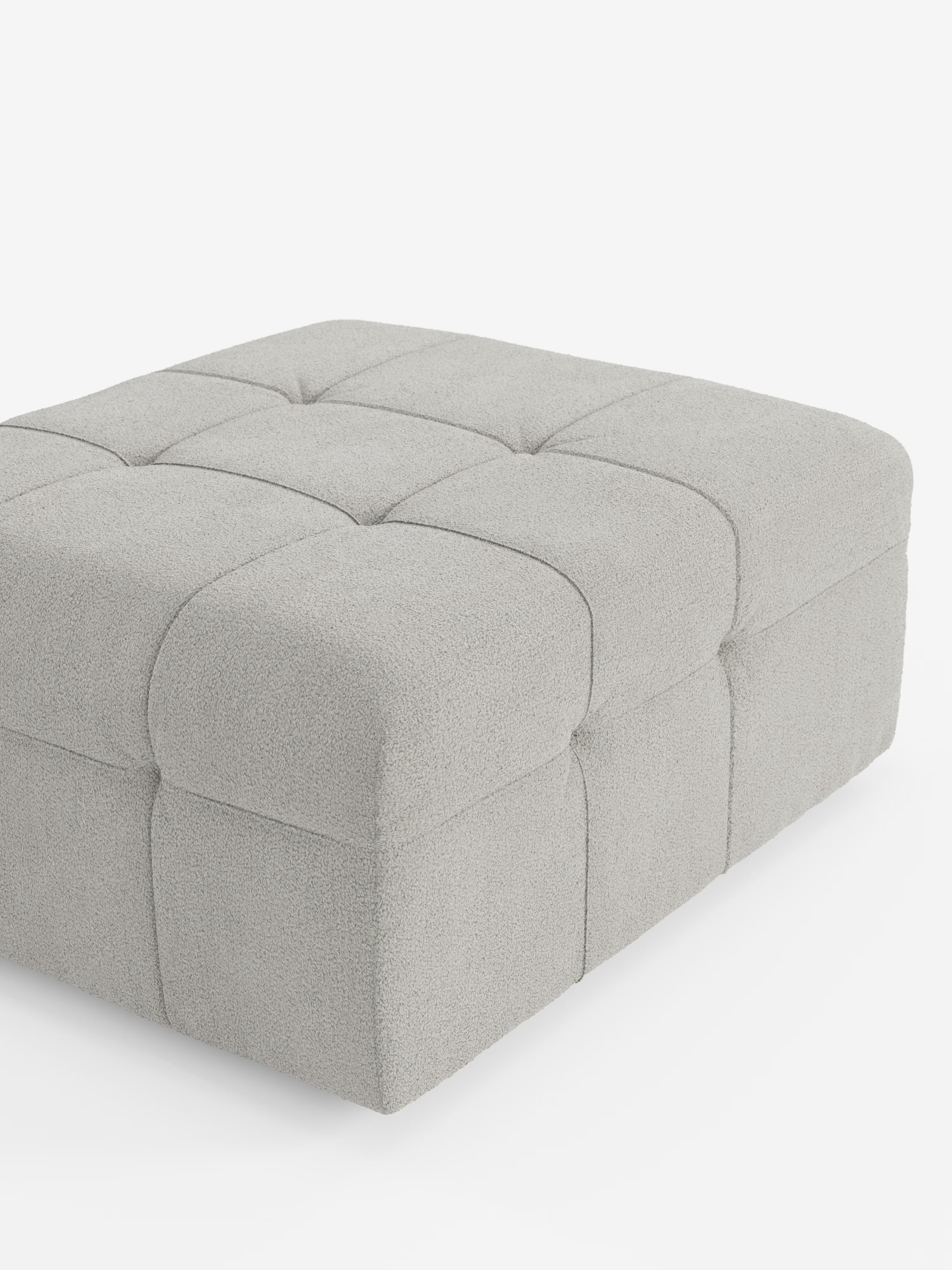 Un raffinato pouf quadrato color grigio chiaro di Divani.Store: il pouf e modulo Mosaic in bouclé è realizzato in morbido tessuto T21 resistente alle macchie e dalla trama ricca, con una profonda trapuntatura capitonné a griglia. Gli angoli arrotondati aggiungono un tocco contemporaneo, mentre viene presentato parzialmente di profilo su uno sfondo bianco a tinta unita: sapientemente realizzato in Italia per coniugare alla perfezione comfort e stile moderno.
