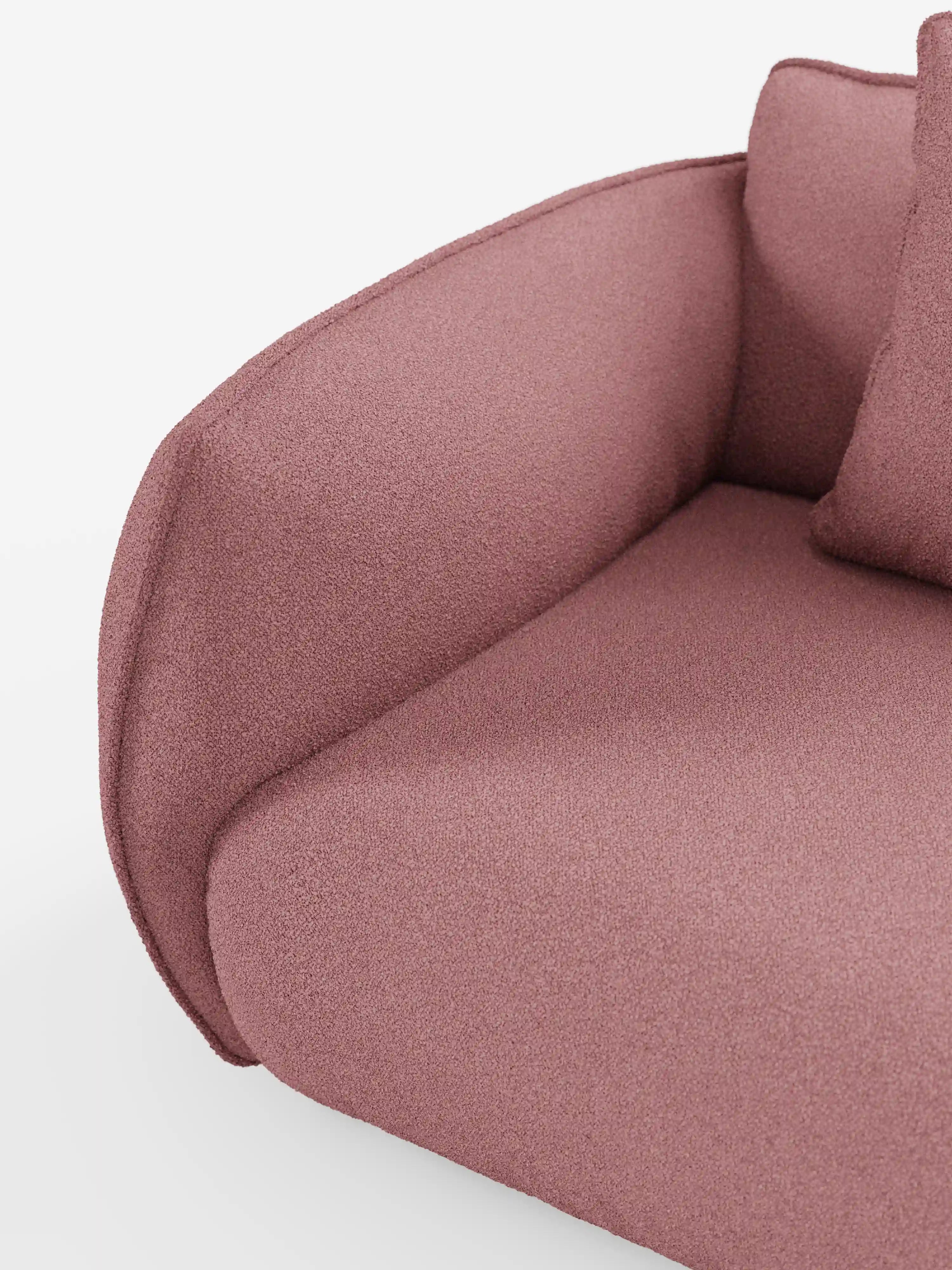 Un primo piano del divano modulare a 3 posti Nimbus di Divani.Store, realizzato in morbido tessuto smacchiabile effetto cotone T33, caratterizzato da un rivestimento rosa testurizzato con braccioli arrotondati e cuscini di seduta. L’immagine mostra una parte dello schienale e un cuscino decorativo abbinato su uno sfondo bianco. Il tessuto morbido e soffice ne esalta la versatilità e il comfort, caratteristiche tipiche dei divani componibili di alta qualità.