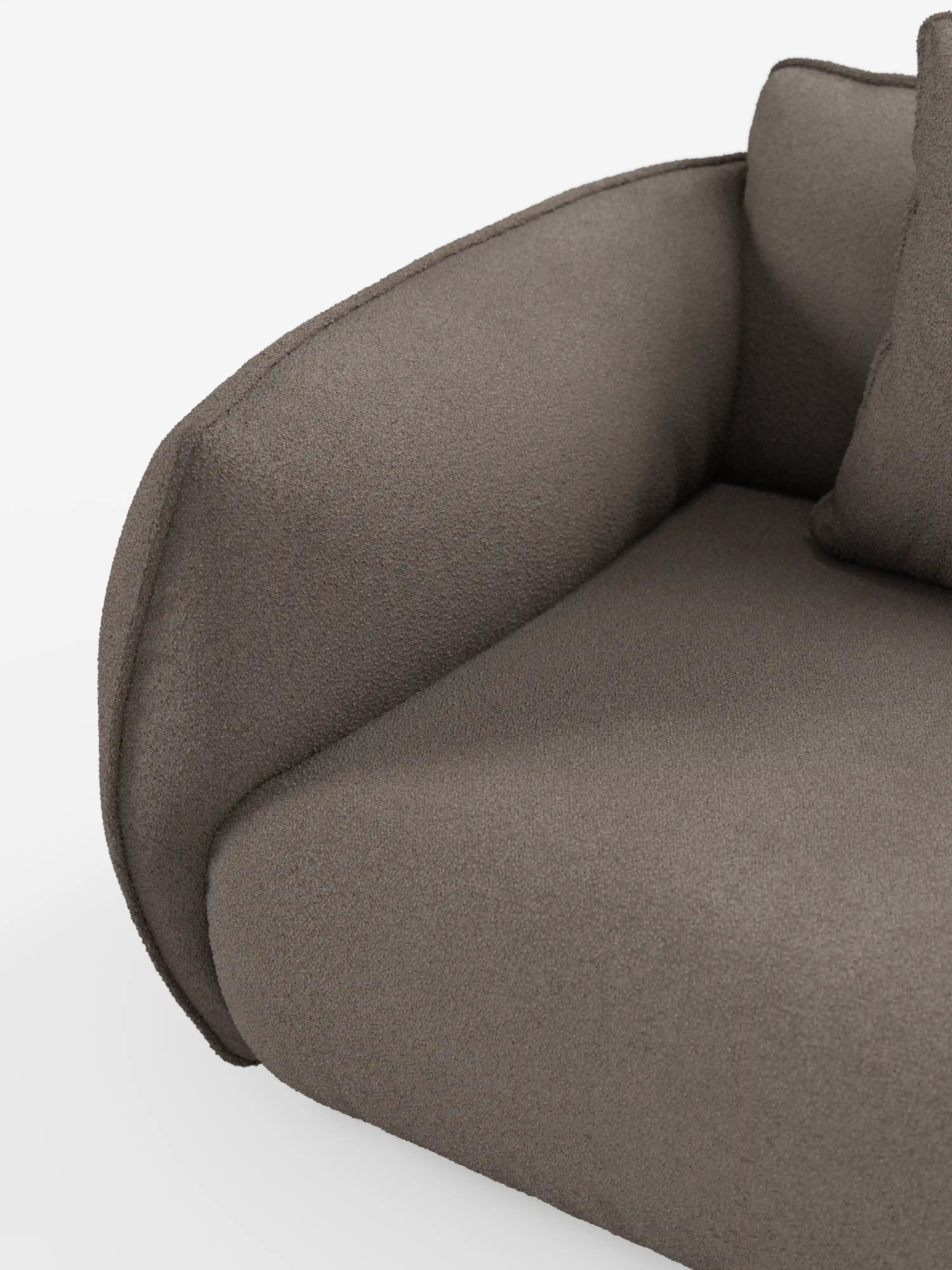 Primo piano del divano modulare a 3 posti “Nimbus” di Divani.Store, rivestito in morbido tessuto T33 effetto cotone, resistente alle macchie, in grigio-marrone scuro. L’immagine mette in risalto il bracciolo ricurvo, il cuscino della seduta e parte dello schienale su uno sfondo bianco a tinta unita. Il design è caratterizzato da un’imbottitura soffice, bordi morbidi e uno stile contemporaneo e minimalista.
