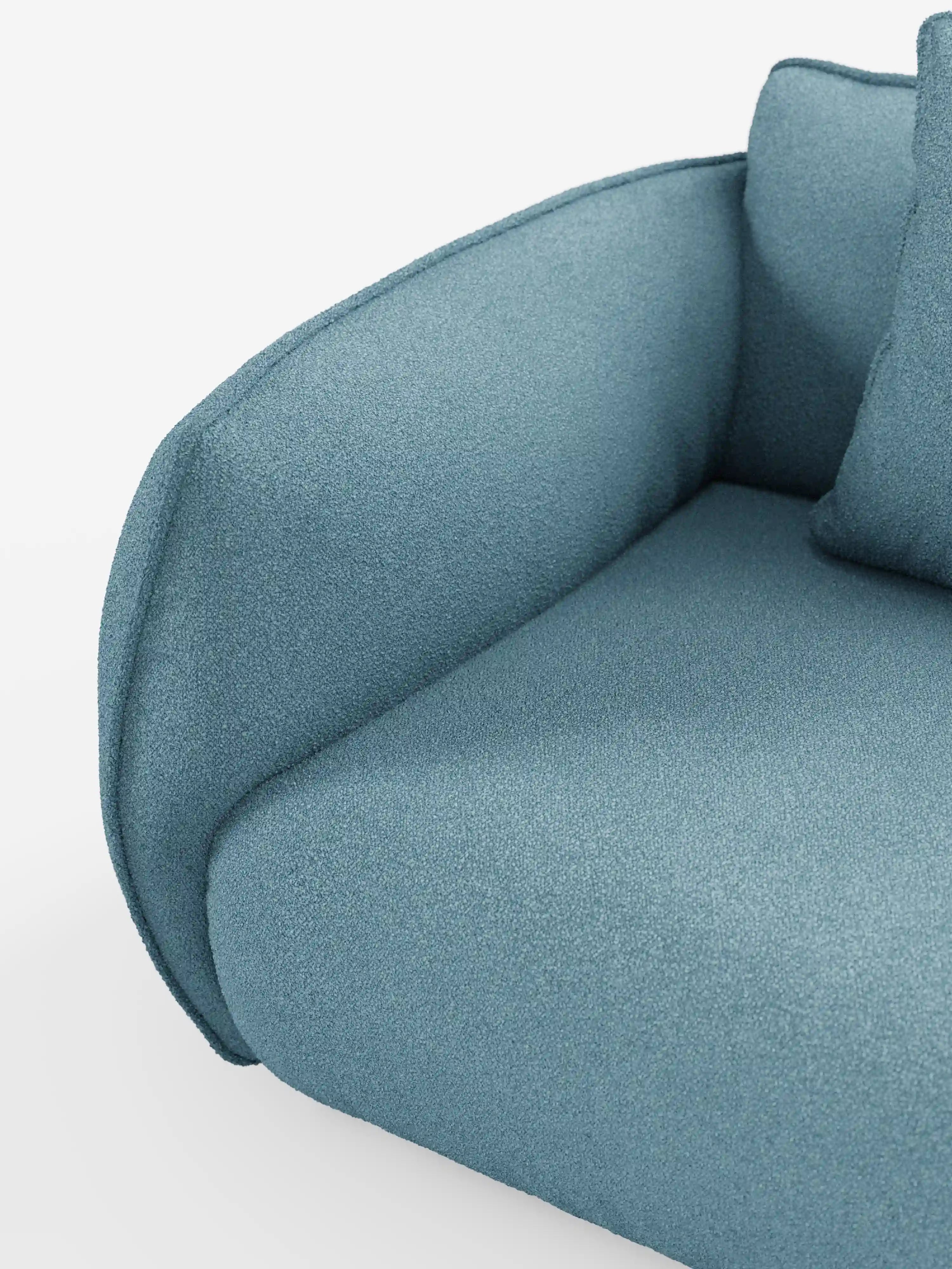 Primo piano del divano modulare a 3 posti “Nimbus” di Divani.Store, rivestito in morbido tessuto T33 effetto cotone, resistente alle macchie, in colore blu. L’immagine mette in risalto il bracciolo ricurvo, il cuscino della seduta e parte di un cuscino dello schienale su uno sfondo bianco, sottolineando il design elegante e minimalista del divano.