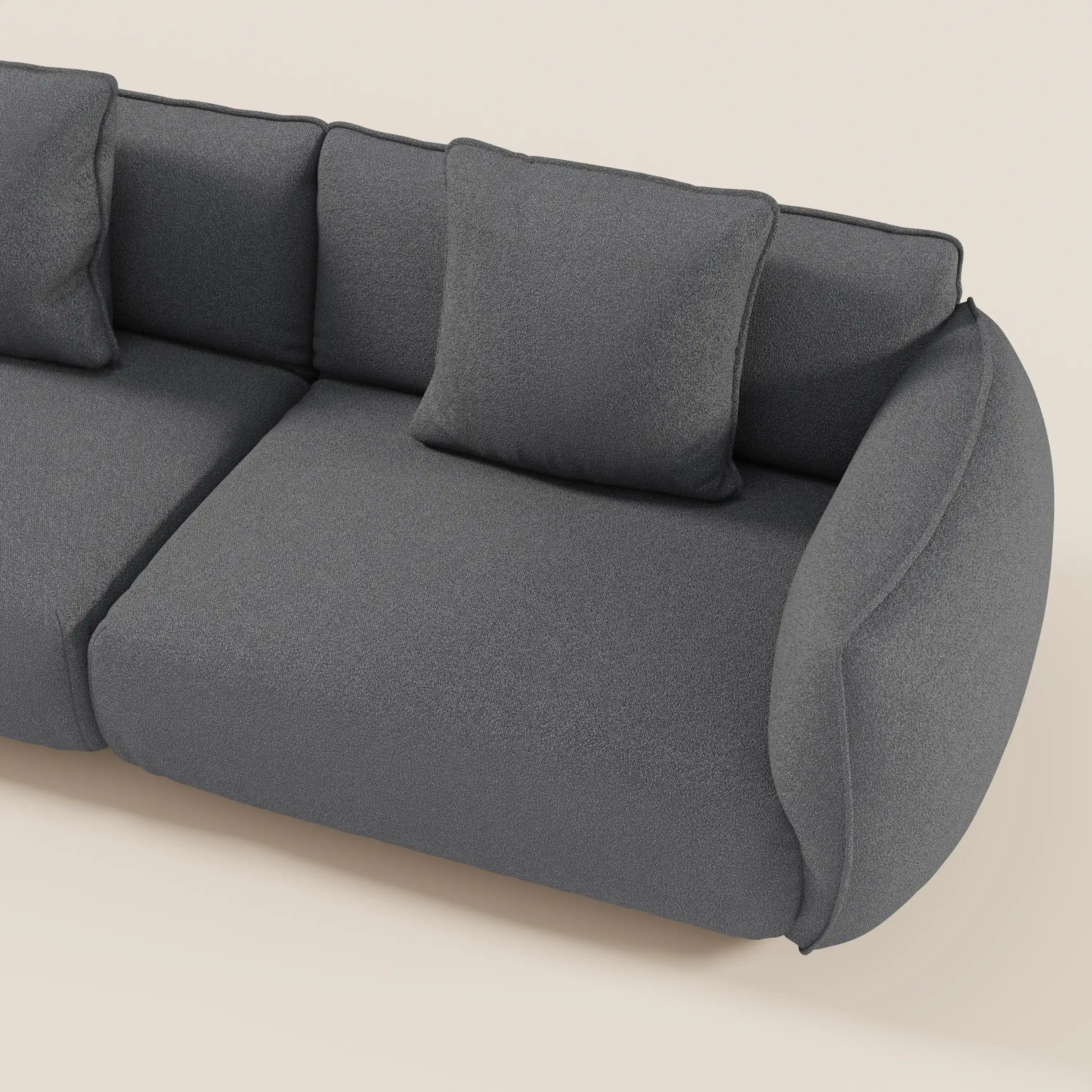 Il divano modulare a 3 sedute componibile Nimbus di Divani.Store, in tessuto effetto cotone smacchiabile grigio scuro, è caratterizzato da bordi arrotondati, cuscini in feltro con cuscino quadrato per lo schienale e bracciolo curvo. Di questo divano completamente sfoderabile è visibile solo una parte.