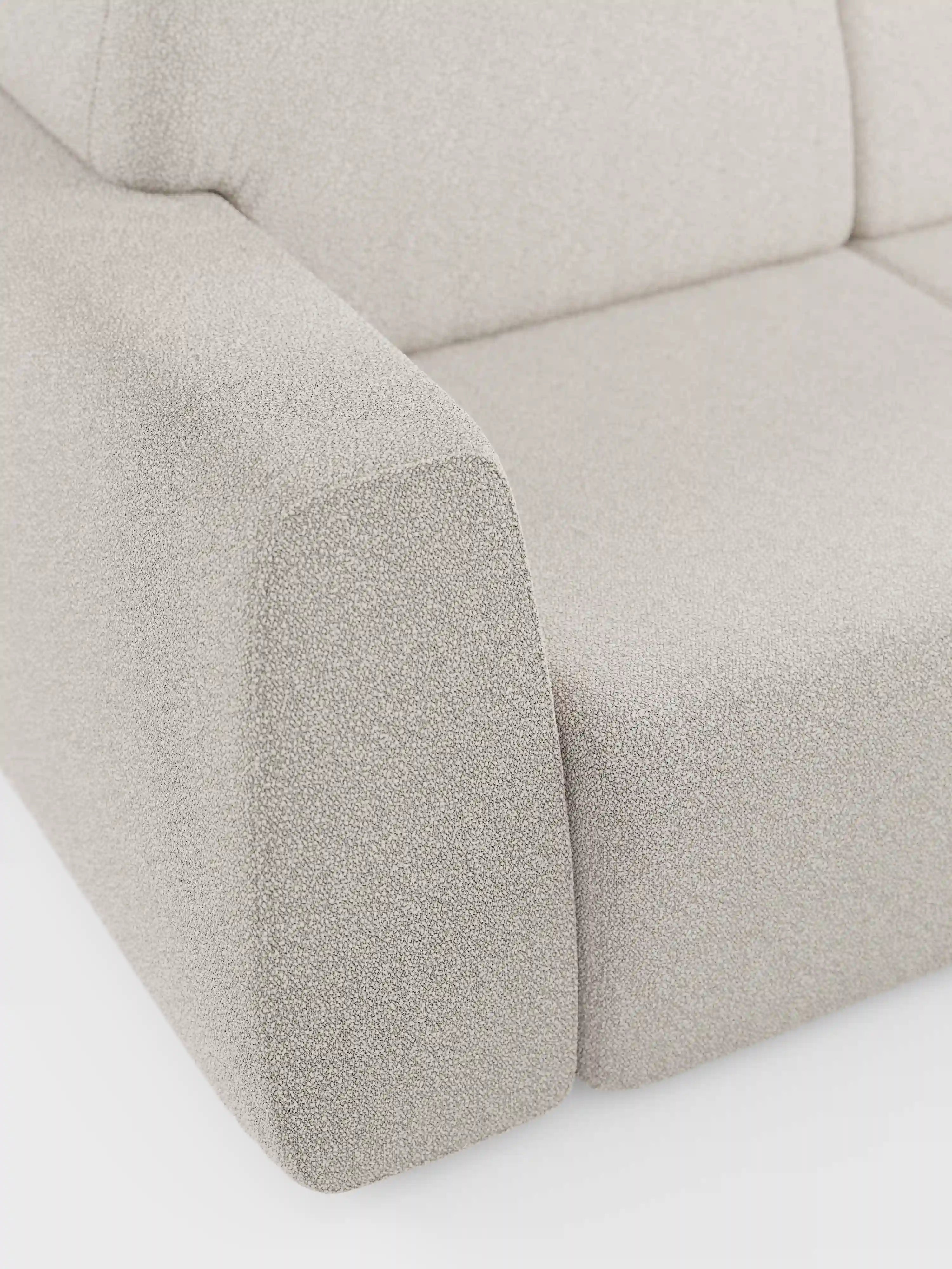 Primo piano del divano Orbit a 2 e 3 posti con sedute scorrevoli di Divani.Store, rivestito in tessuto smacchiabile effetto cotone T33 color beige chiaro. L'immagine mette in risalto il bracciolo sinistro e il cuscino della seduta, evidenziando il tessuto sfoderabile morbido, dalla trama rigata e dalla trama fitta. L’attenzione è rivolta alle linee pulite e alle curve morbide di Orbit, che ne esemplificano il design moderno.