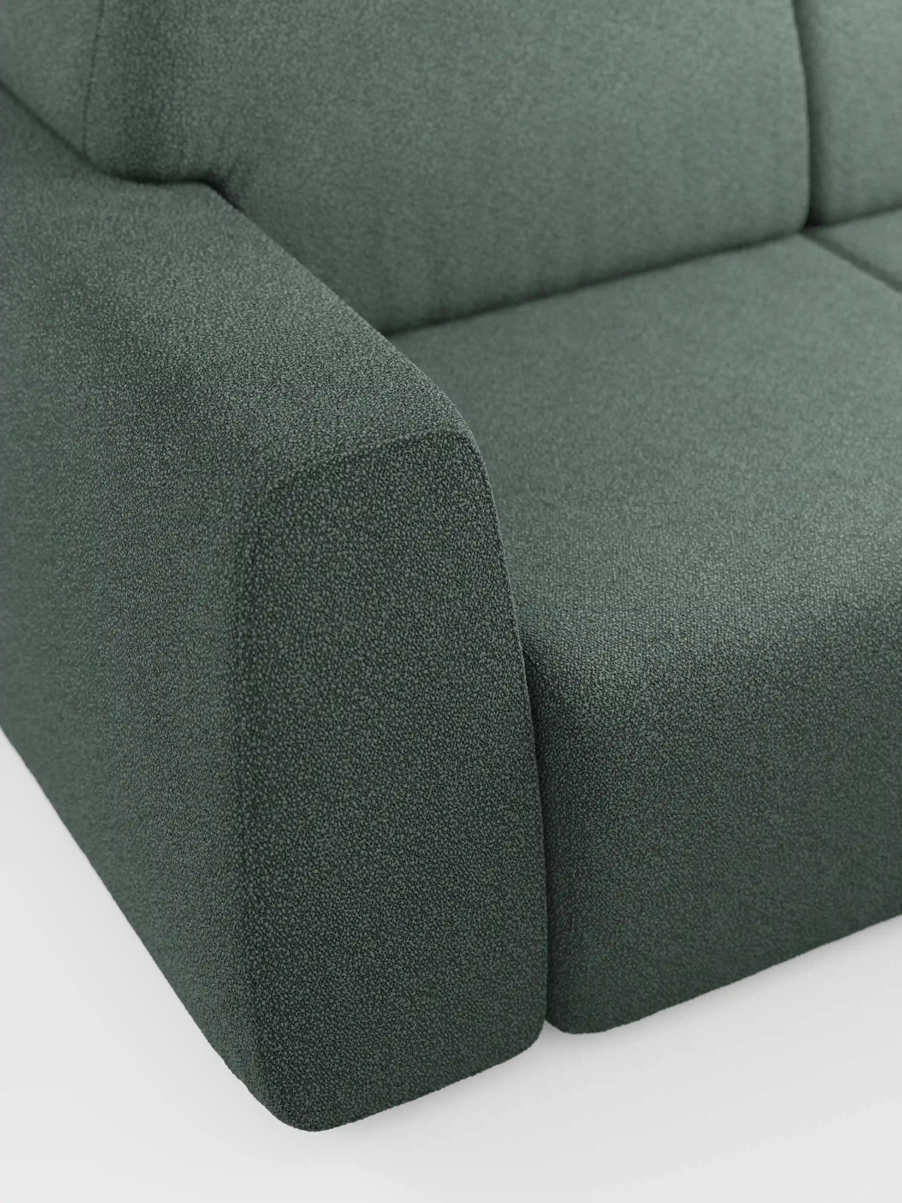 Primo piano di un divano a tre posti Orbit di Divani.Store, realizzato in tessuto verde scuro con trama in rilievo e rivestito in T33, un tessuto rimovibile effetto cotone resistente alle macchie. L'immagine mette in risalto i cuscini dei braccioli, della seduta e dello schienale di questo modello moderno dalle linee squadrate e dai bordi lisci e puliti. Lo sfondo è una superficie bianca a tinta unita.