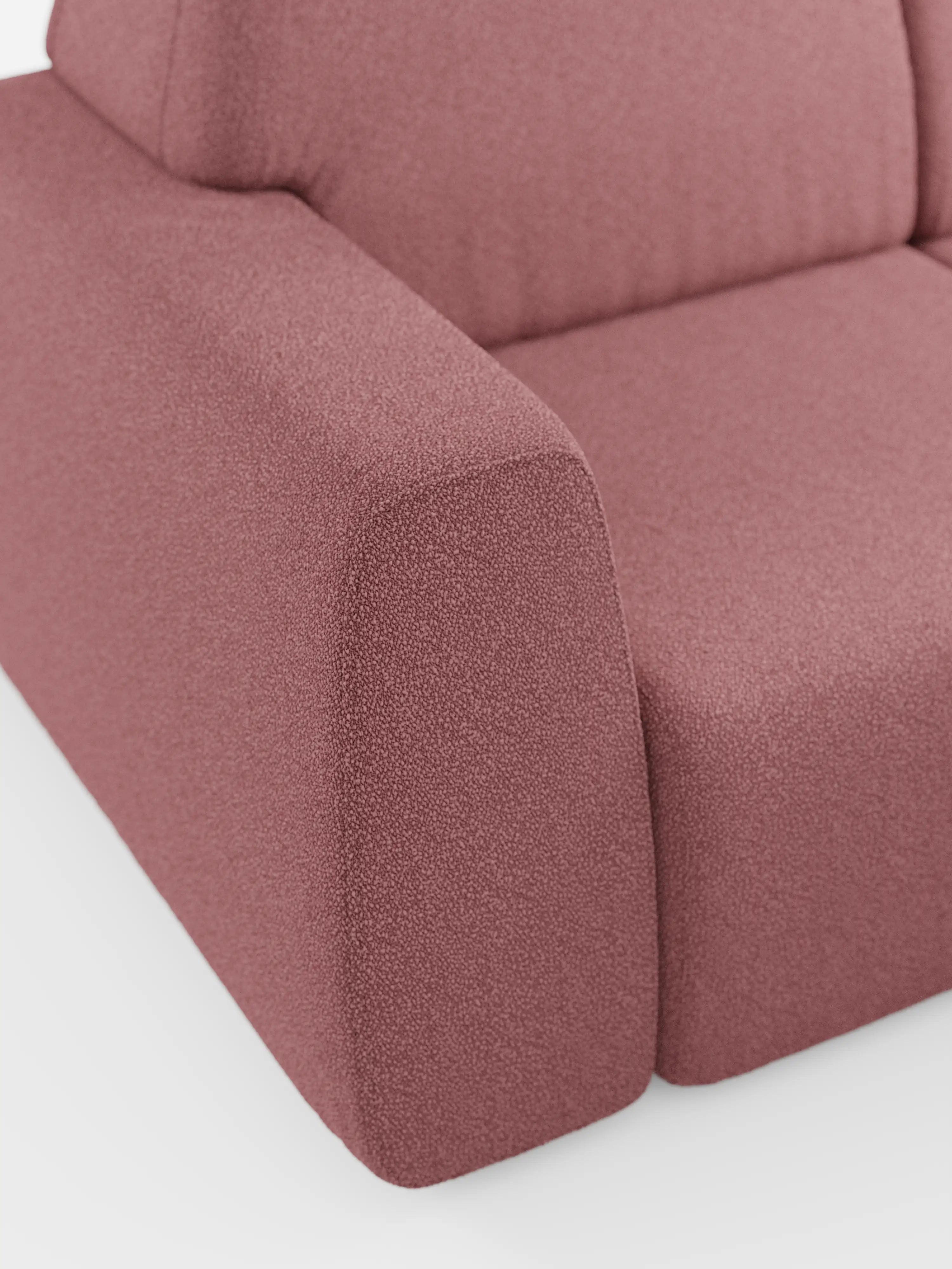 Primo piano del divano angolare Orbit con penisola reversibile e tutte le sedute allungabili di Divani.Store, rivestito in tessuto effetto cotone (T33) color rosa polveroso testurizzato e resistente alle macchie. L’immagine mette a fuoco il bracciolo, la seduta e parte dello schienale, sottolineandone le linee pulite, la superficie liscia e il design minimalista — elementi distintivi dell’arredamento di alta gamma. Lo sfondo è una superficie bianca a tinta unita.