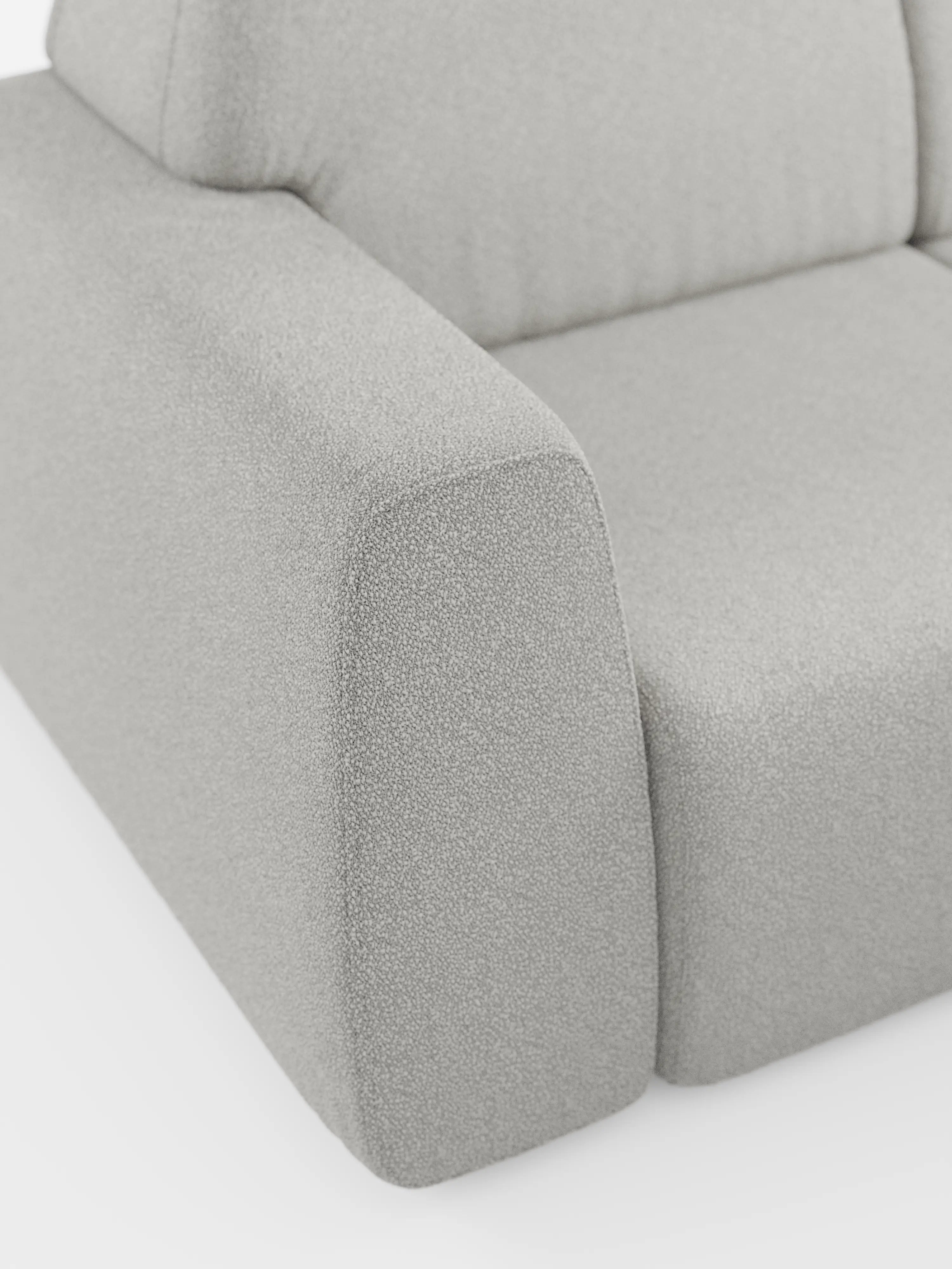 Primo piano di un divano angolare Orbit di colore grigio chiaro e dal design moderno, con penisola reversibile e tutte le sedute allungabili, rivestito in tessuto smacchiabile effetto cotone T33 di Divani.Store, che mostra una parte della seduta, dello schienale e del bracciolo. Il tessuto presenta un aspetto morbido e strutturato che ricorda il cotone. Le linee del divano sono morbide e arrotondate, a sottolineare il suo design minimalista e contemporaneo. Lo sfondo è bianco.