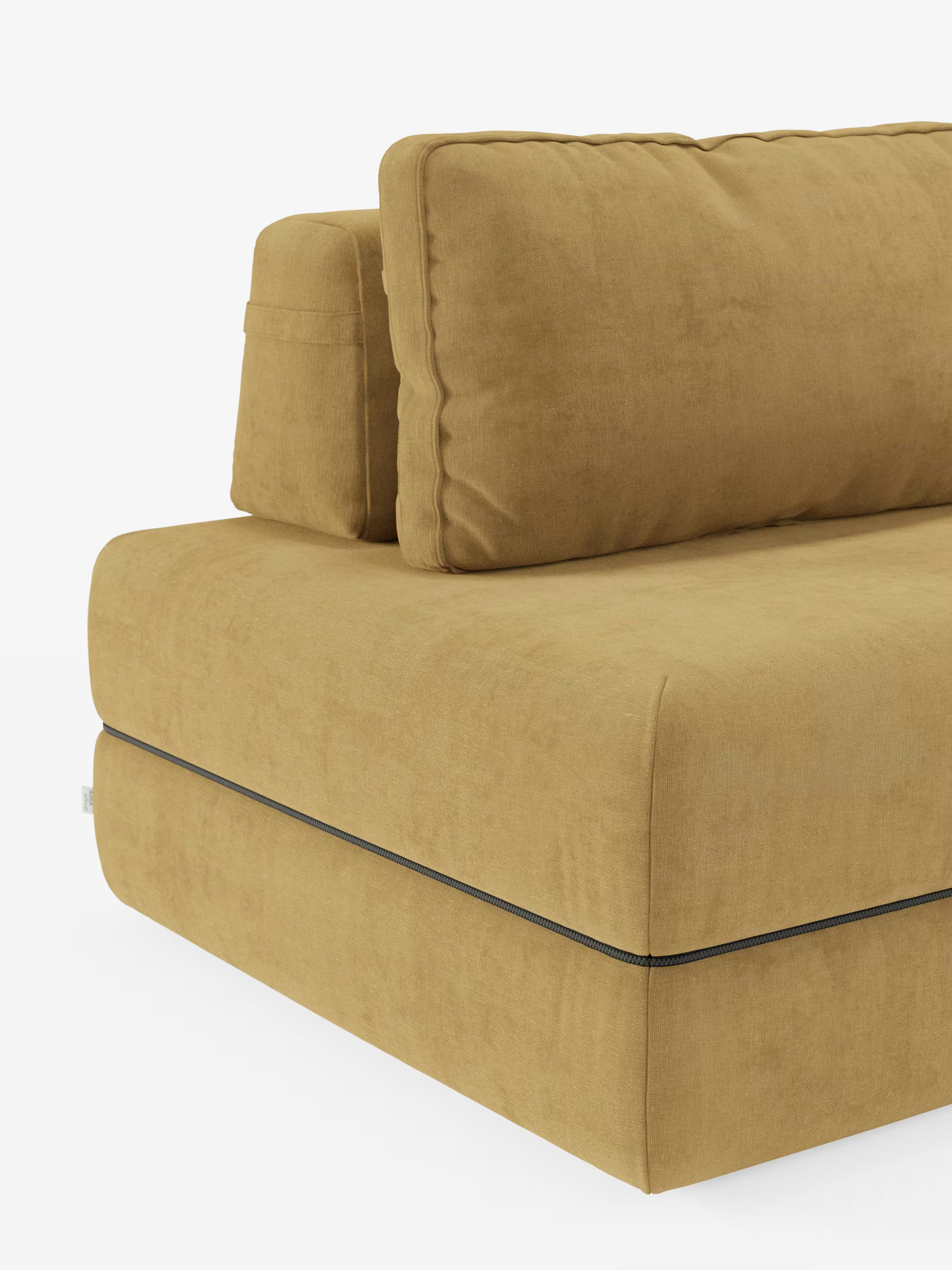 Un primo piano del divano letto matrimoniale Rift, disponibile nelle versioni a 2 e 3 posti con schienali mobili, in colore giallo senape, di Divani.Store, mostra l'angolo con un cuscino di seduta spesso, un ampio cuscino dello schienale e un cuscino laterale compatto. Il rivestimento è realizzato in morbido tessuto T31 resistente alle macchie, mentre una sottile cucitura scura corre lungo il bordo vicino alla base. Lo sfondo è bianco.