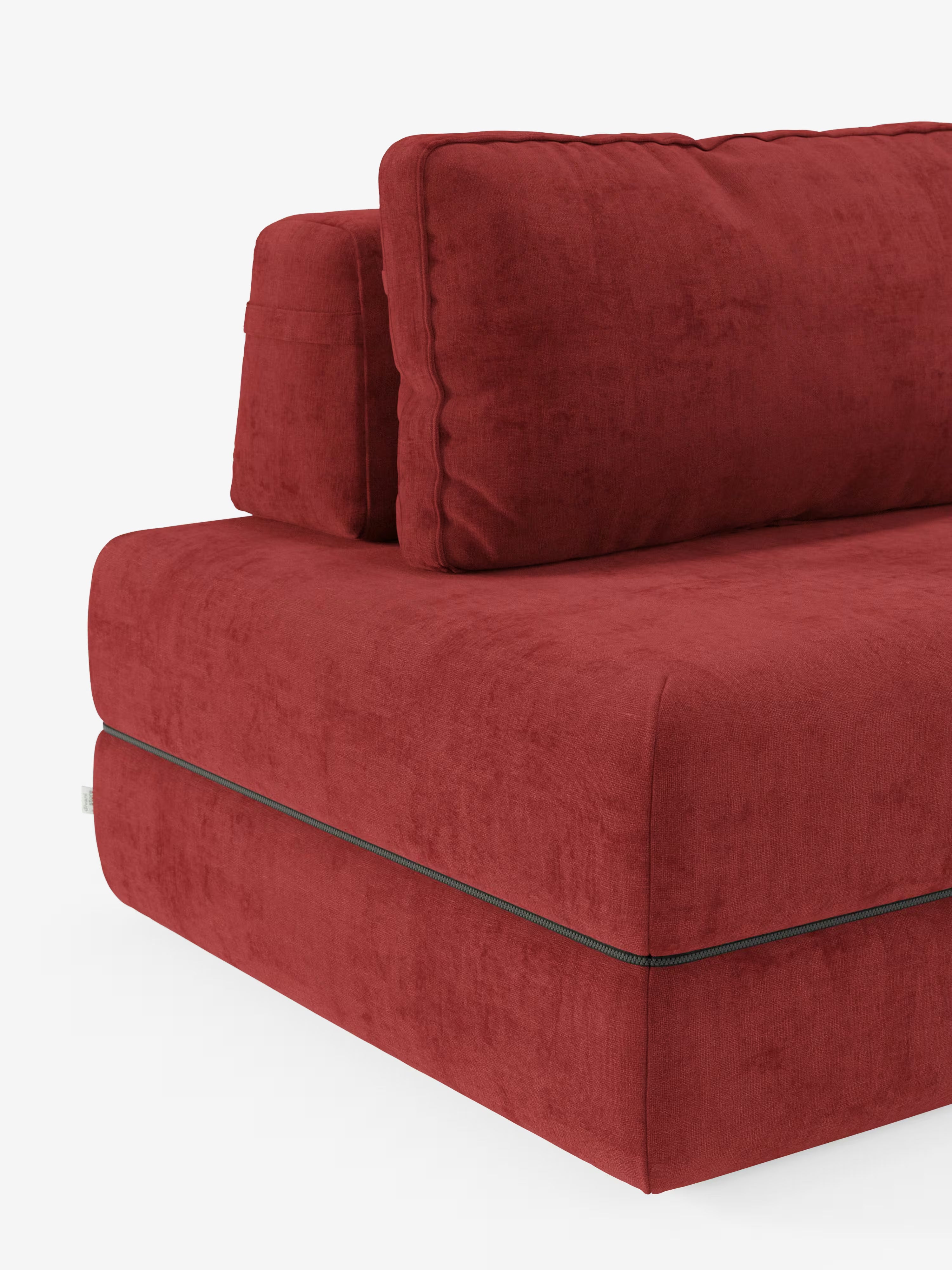 Un primo piano del divano letto matrimoniale Rift a 2 e 3 posti con schienali mobili di Divani.Store mette in risalto i cuscini spessi e morbidi di colore rosso, rivestiti in tessuto T31 antimacchia, con una cerniera nera a vista lungo il bordo inferiore. Sullo sfondo bianco, il colore intenso e la morbida consistenza del divano risaltano, mettendo in risalto il suo design moderno e l'alto materasso in memory foam da 24 cm.