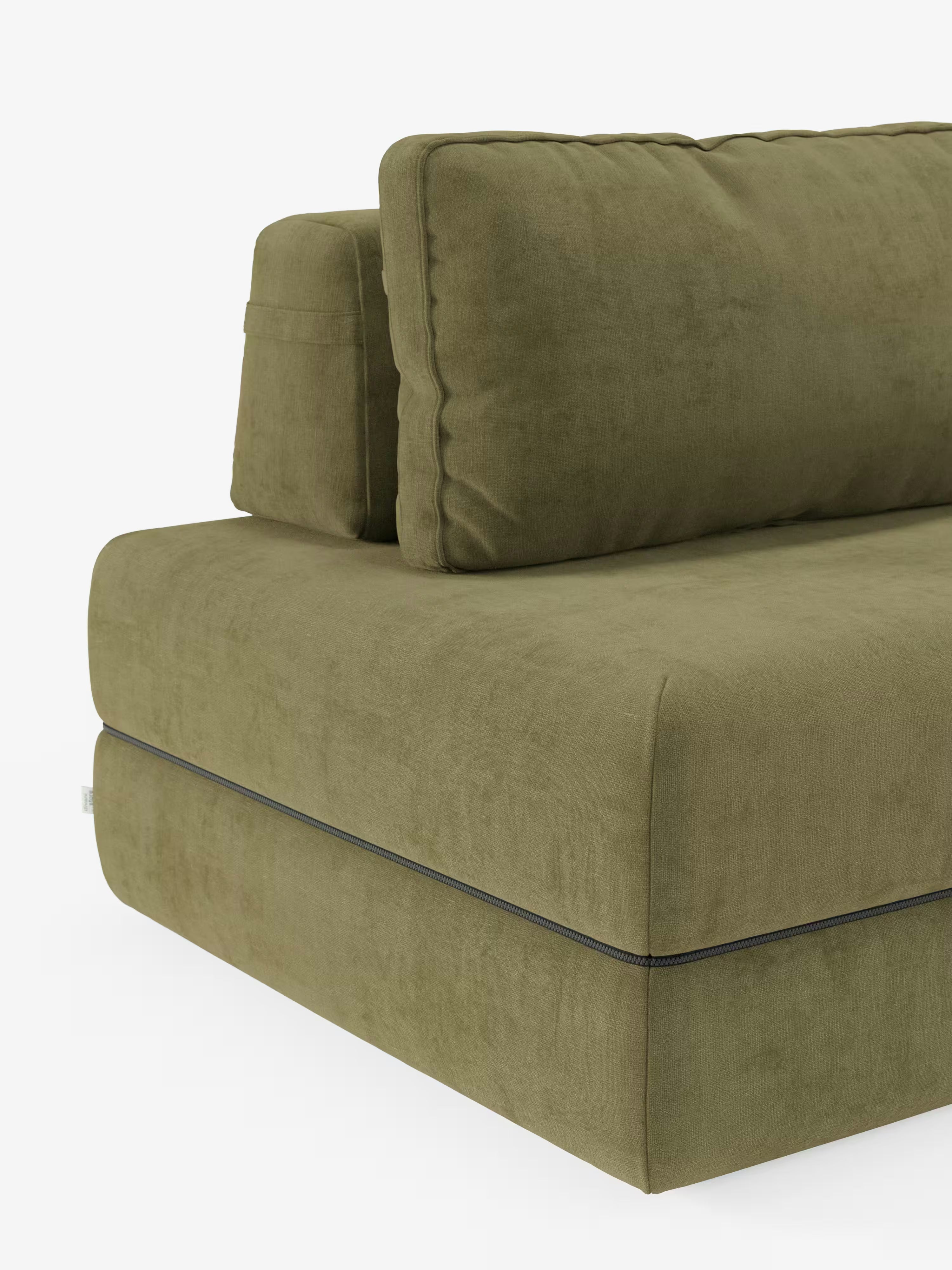 Primo piano del divano letto matrimoniale Rift di Divani.Store in verde oliva, caratterizzato da un design moderno con morbidi cuscini rettangolari per la seduta e lo schienale. Rivestito in tessuto T31 antimacchia dall’aspetto vellutato, il divano presenta una cucitura orizzontale a vista con dettaglio a cerniera lungo il lato della seduta imbottita. Lo sfondo è bianco a tinta unita.