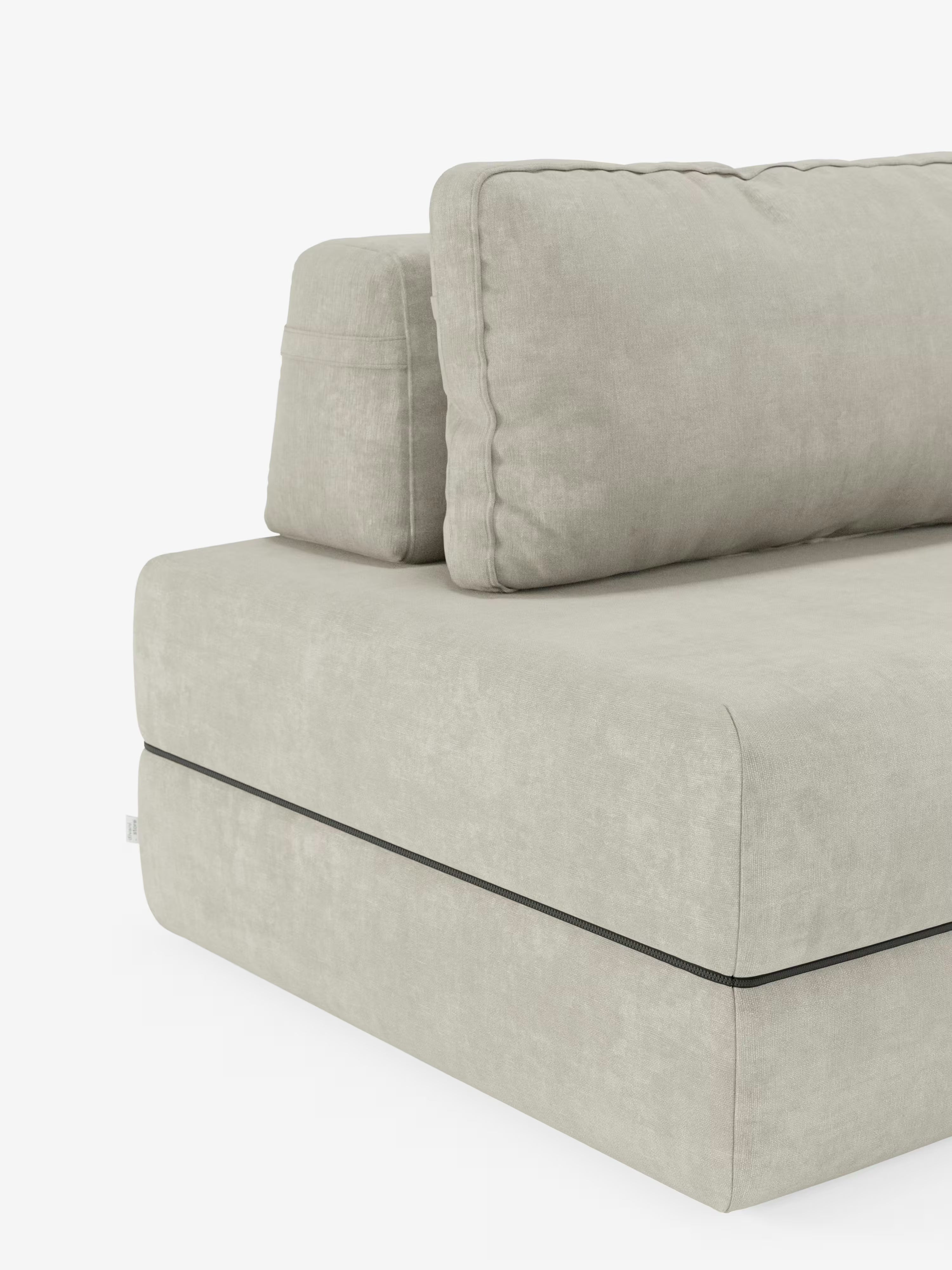 Una poltrona letto Rift color beige chiaro di Divani.Store, dotata di un materasso in memory foam alto 24 cm e di uno schienale regolabile. La sezione modulare presenta ampi e morbidi cuscini di seduta e schienale in tessuto T31, morbido e resistente alle macchie. Le linee dritte e pulite e il bordino nero a contrasto tra la seduta e la base evocano un’eleganza contemporanea. Lo sfondo è bianco a tinta unita.