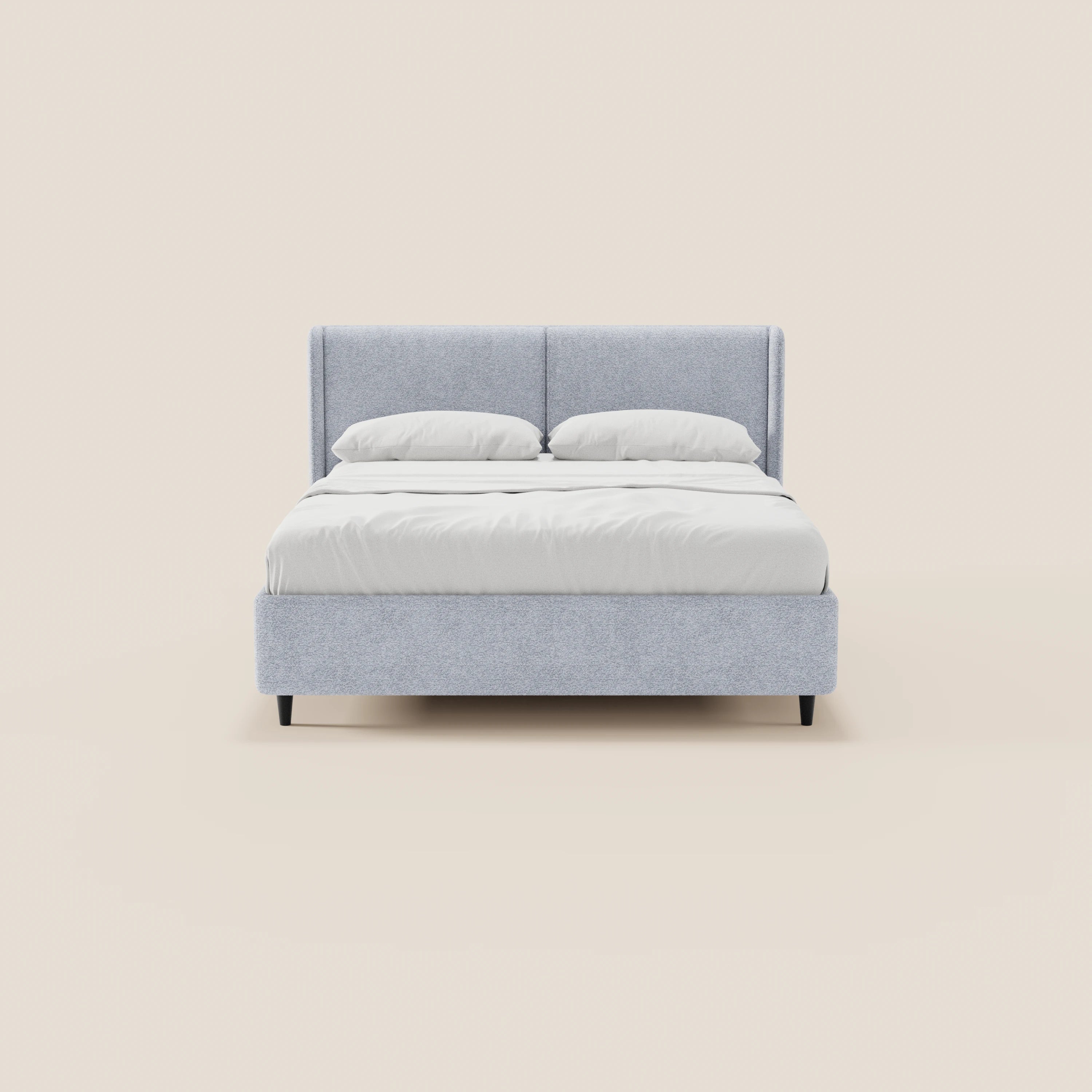 Il letto di design VALKIRIA di Letti.store presenta una struttura imbottita di colore grigio chiaro, una testiera alta e avvolgente, due cuscini bianchi, tessuto certificato Oeko-Tex® e gambe corte nere. Nell’immagine è raffigurato in vista frontale su uno sfondo color crema.